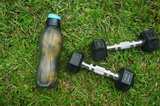 A sports water bottle beside 2 dumbbells