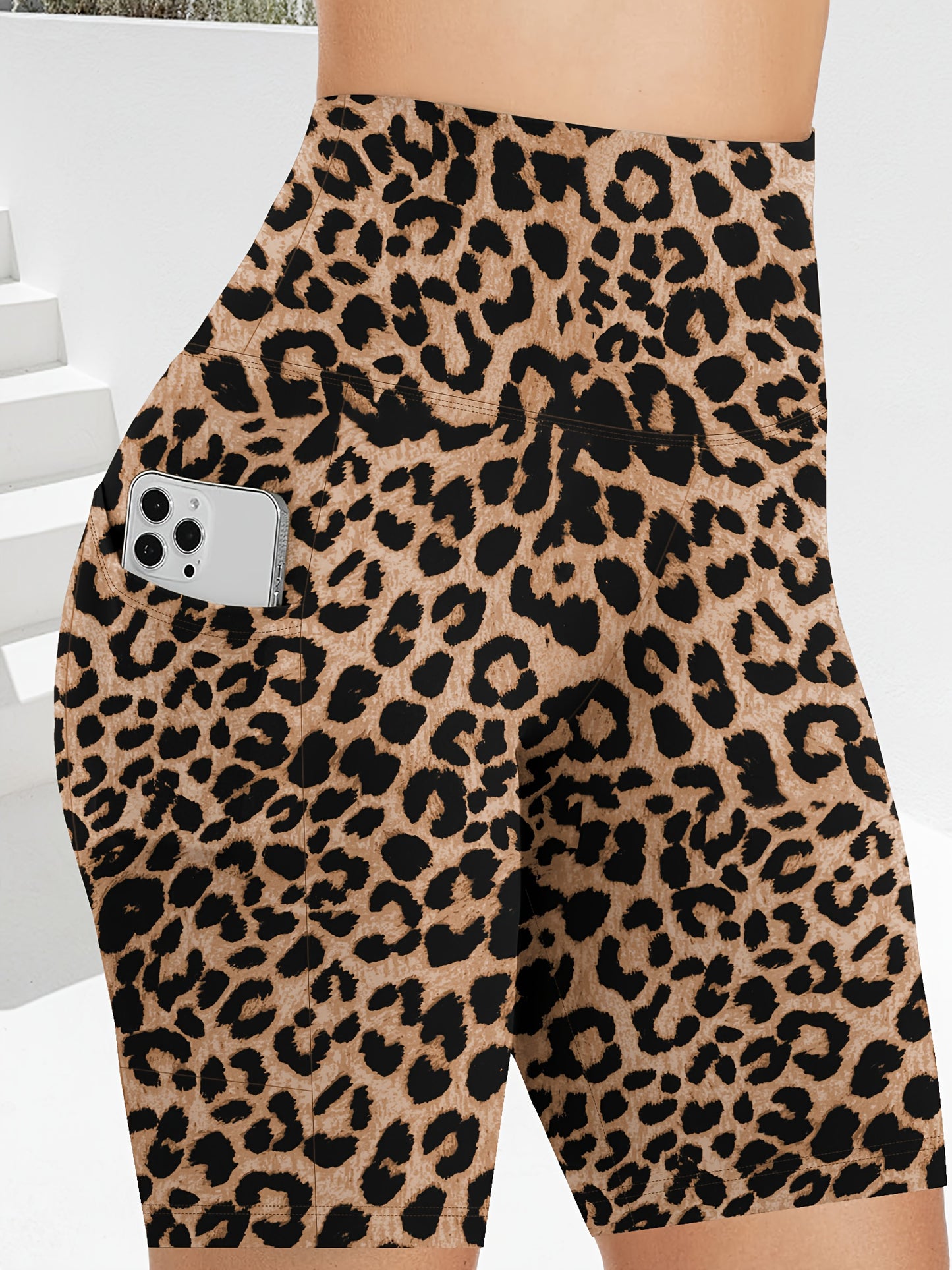 Leopard print women's workout shorts with pockets with a phone pocket on a neutral background