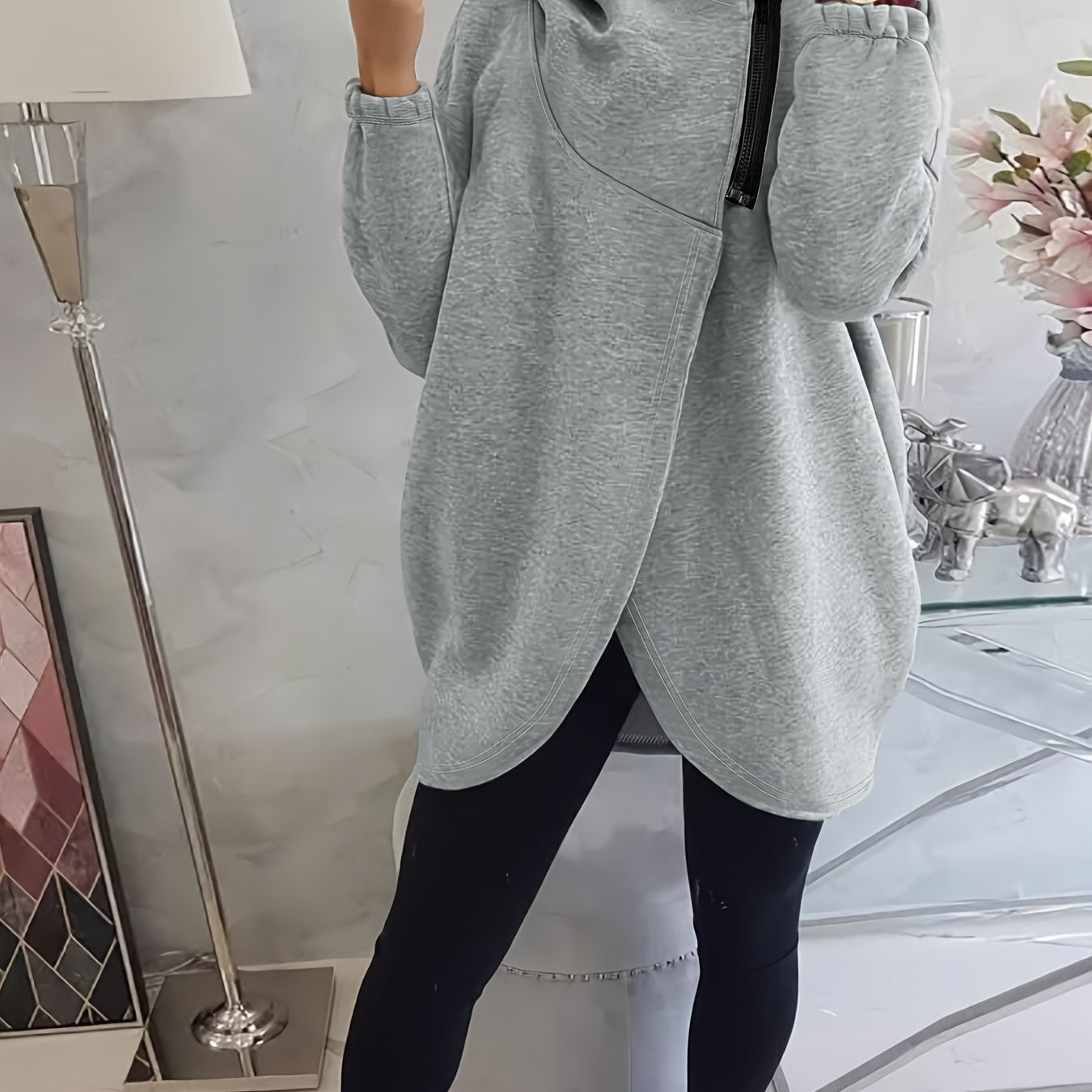 A person wearing a grey women’s oversized zip-up hoodie
