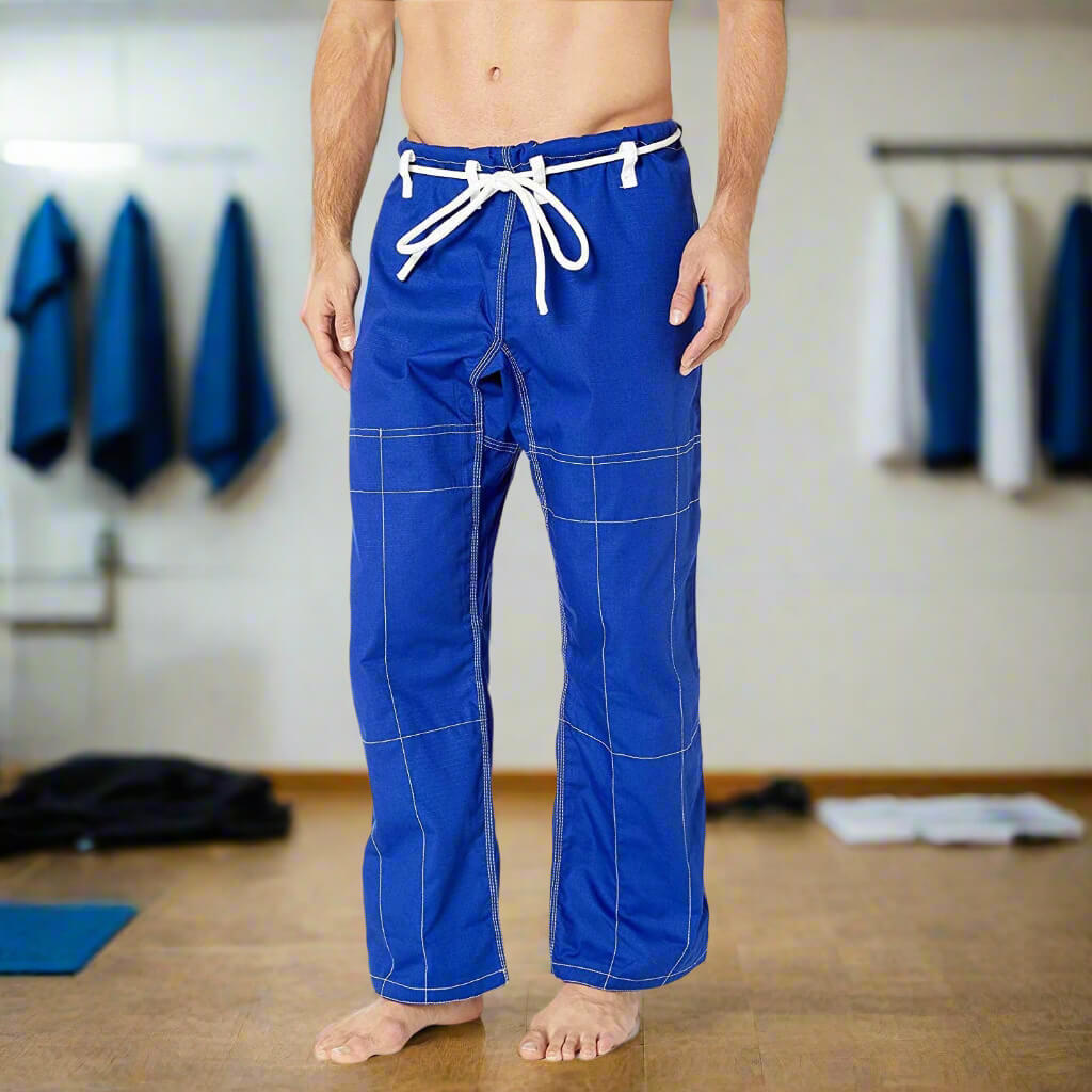 Person wearing blue bjj gi pants with white drawstring in a gym setting