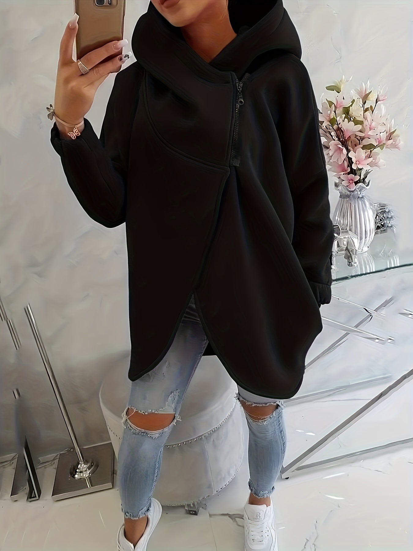 A person wearing a black women’s oversized zip-up hoodie
