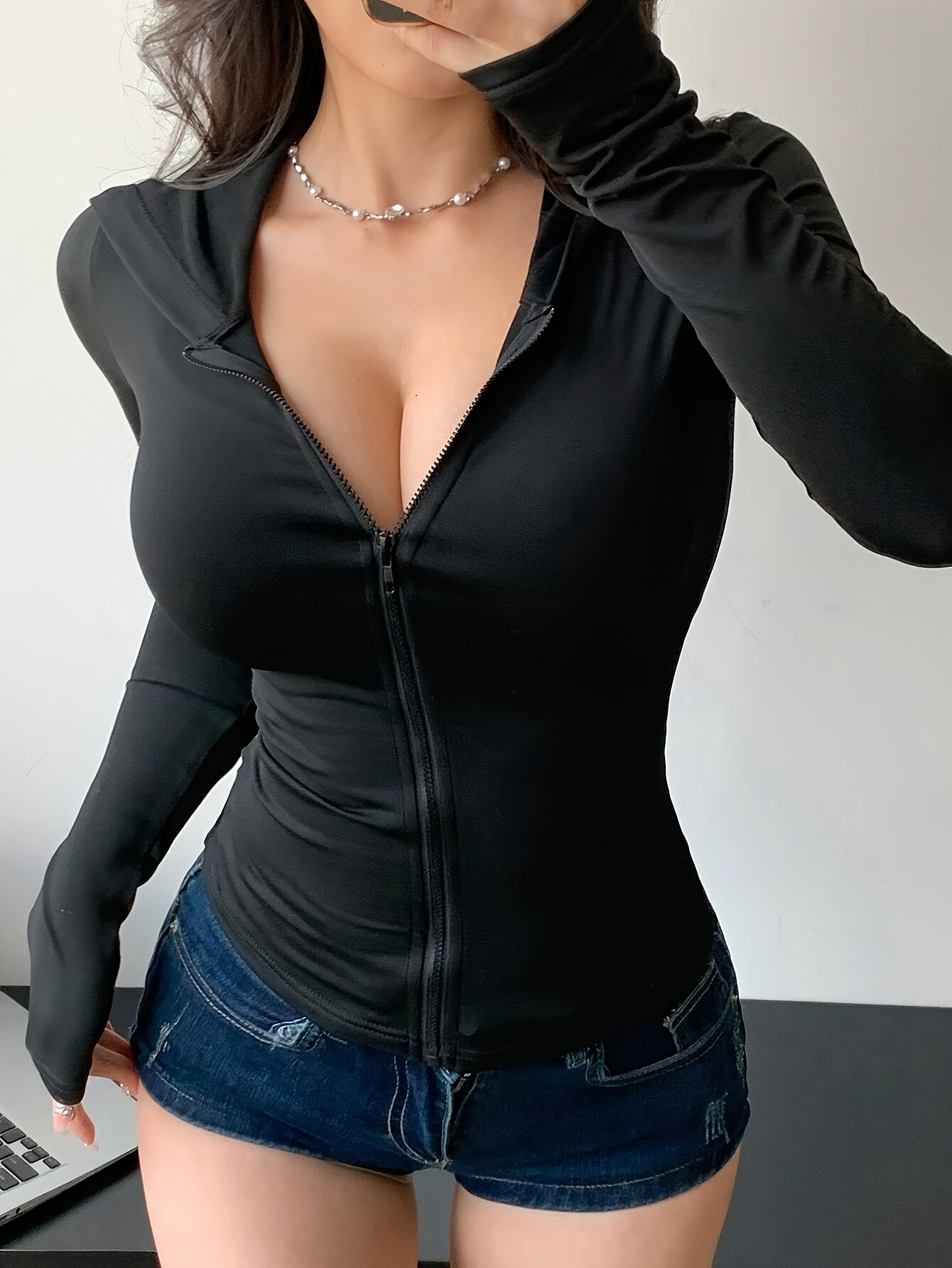 A lady wearing a black women’s hooded zip-up sweatshirt sold by 100 Spartans