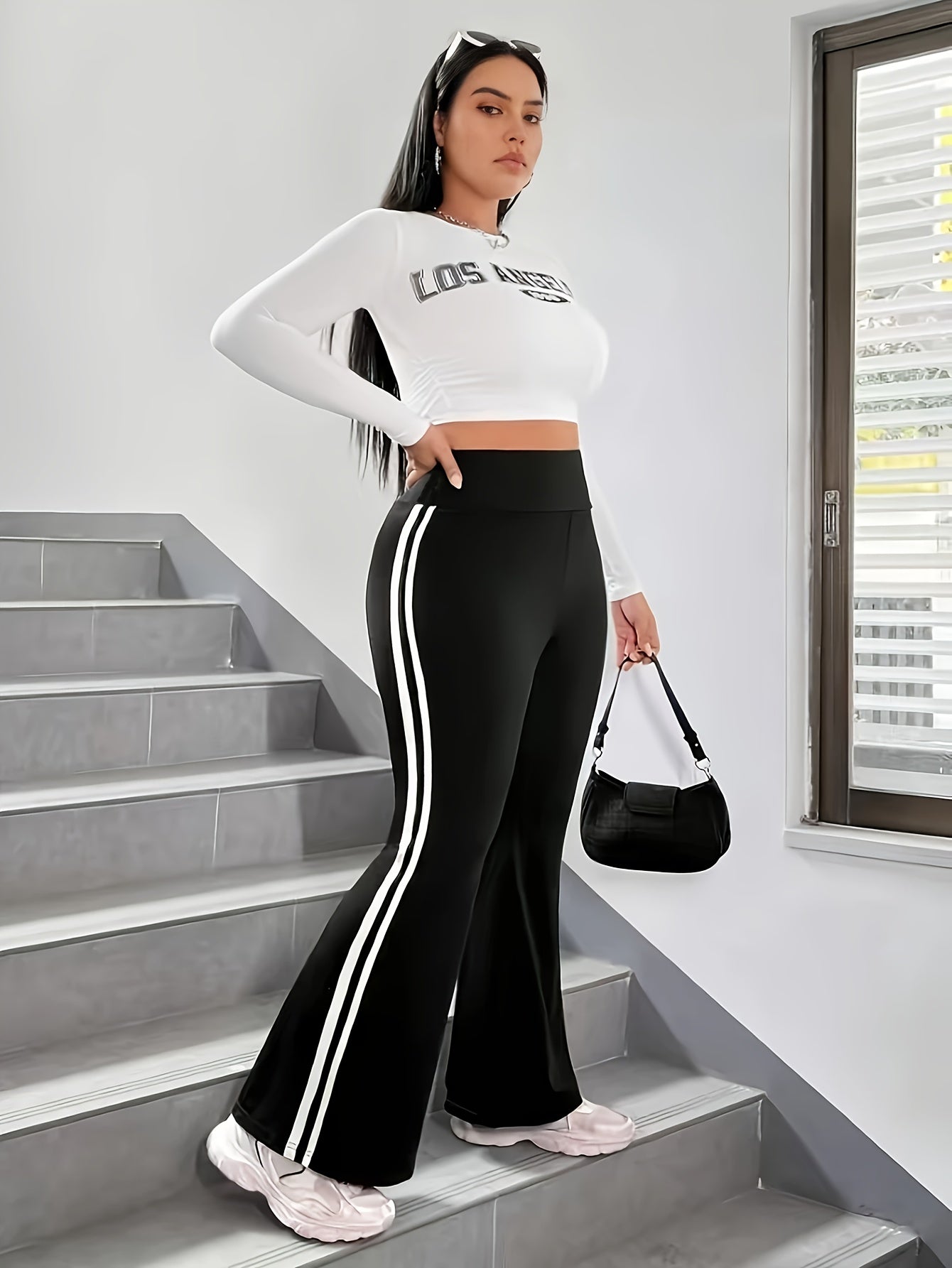 The front view of a woman wearing a women's black and white striped leggings sold by 100 Spartans