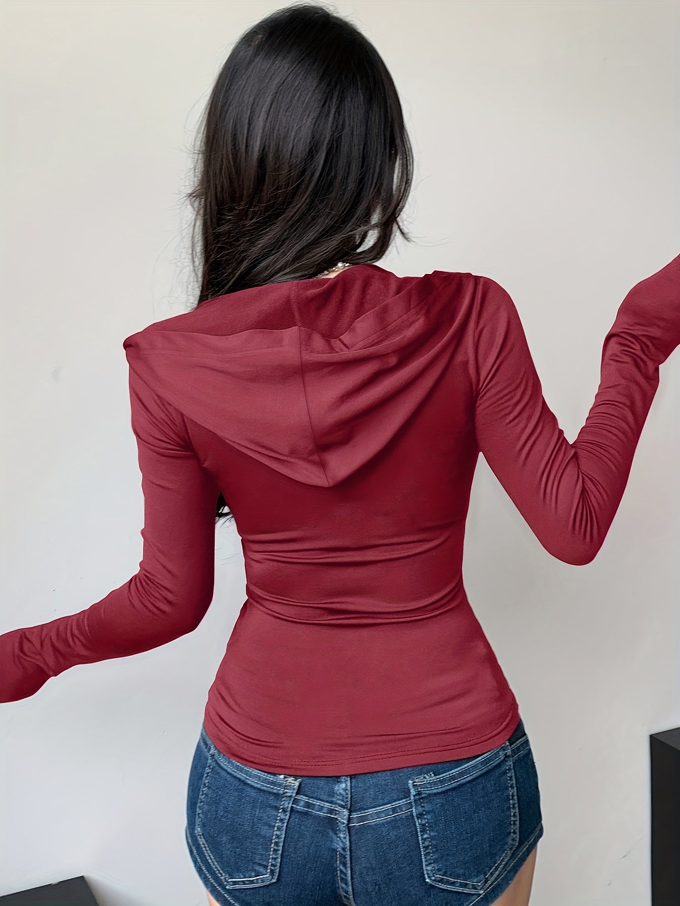 Person wearing a red hoodie and blue jeans against a plain background