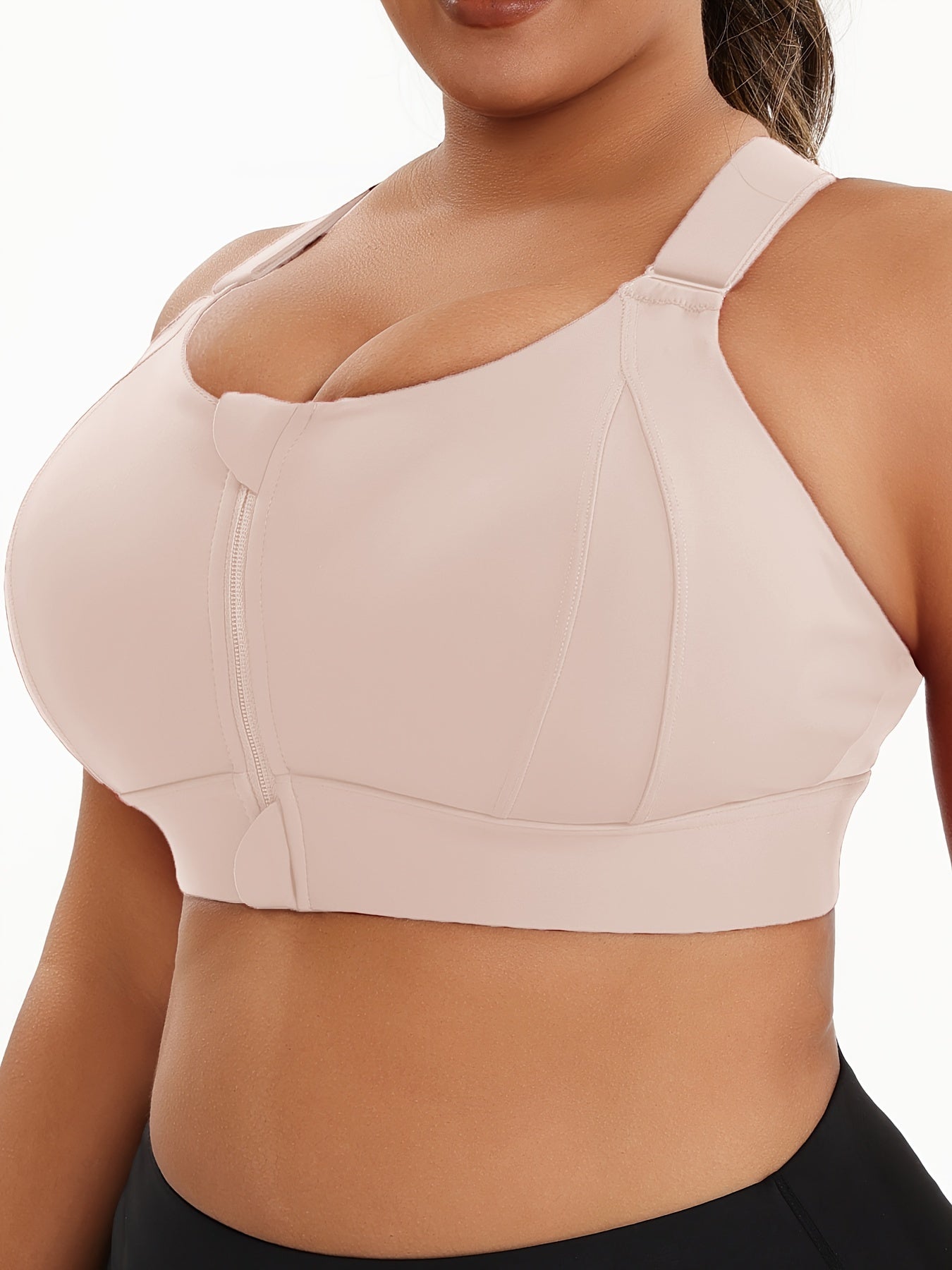 A woman wearing a beige plus size sports bras with criss-cross back design sold by 100 Spartans