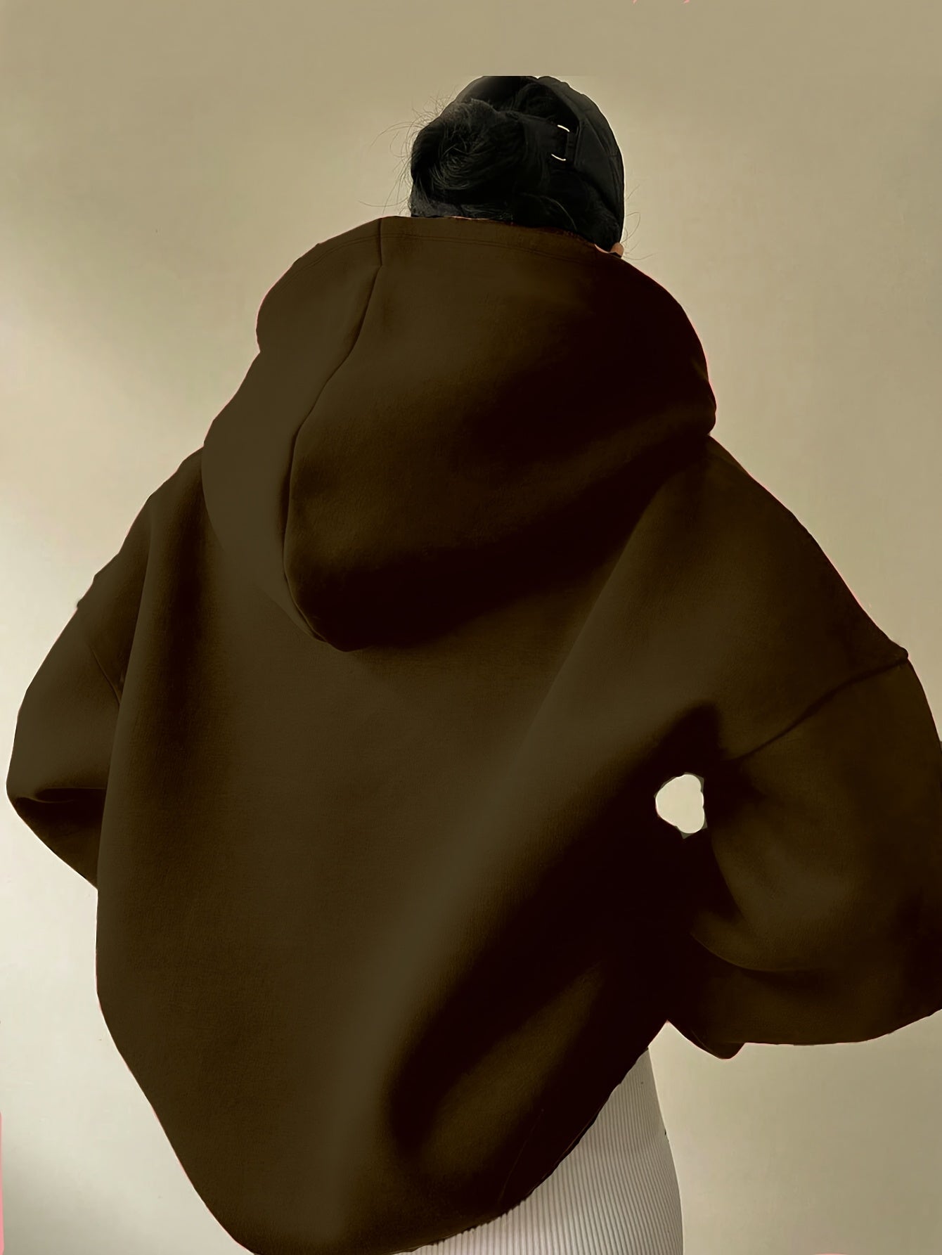 The back view of a woman wearing a camouflage winter hoodie for women sold by 100 Spartans