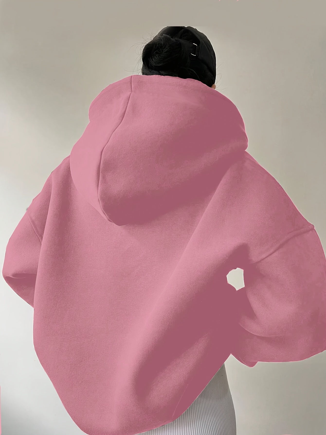 The back view of a woman wearing a pink winter hoodie for women sold by 100 Spartans