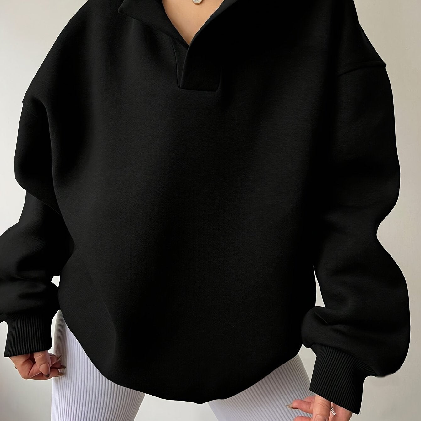 The front view of a woman wearing a black winter hoodie for women sold by 100 Spartans