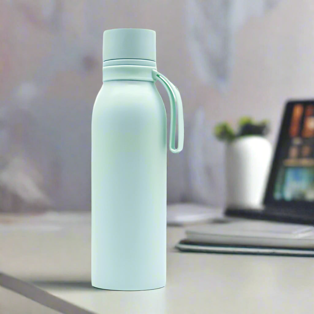 A light green smart water bottles sold by 100 Spartans placed on a work table beside a laptop