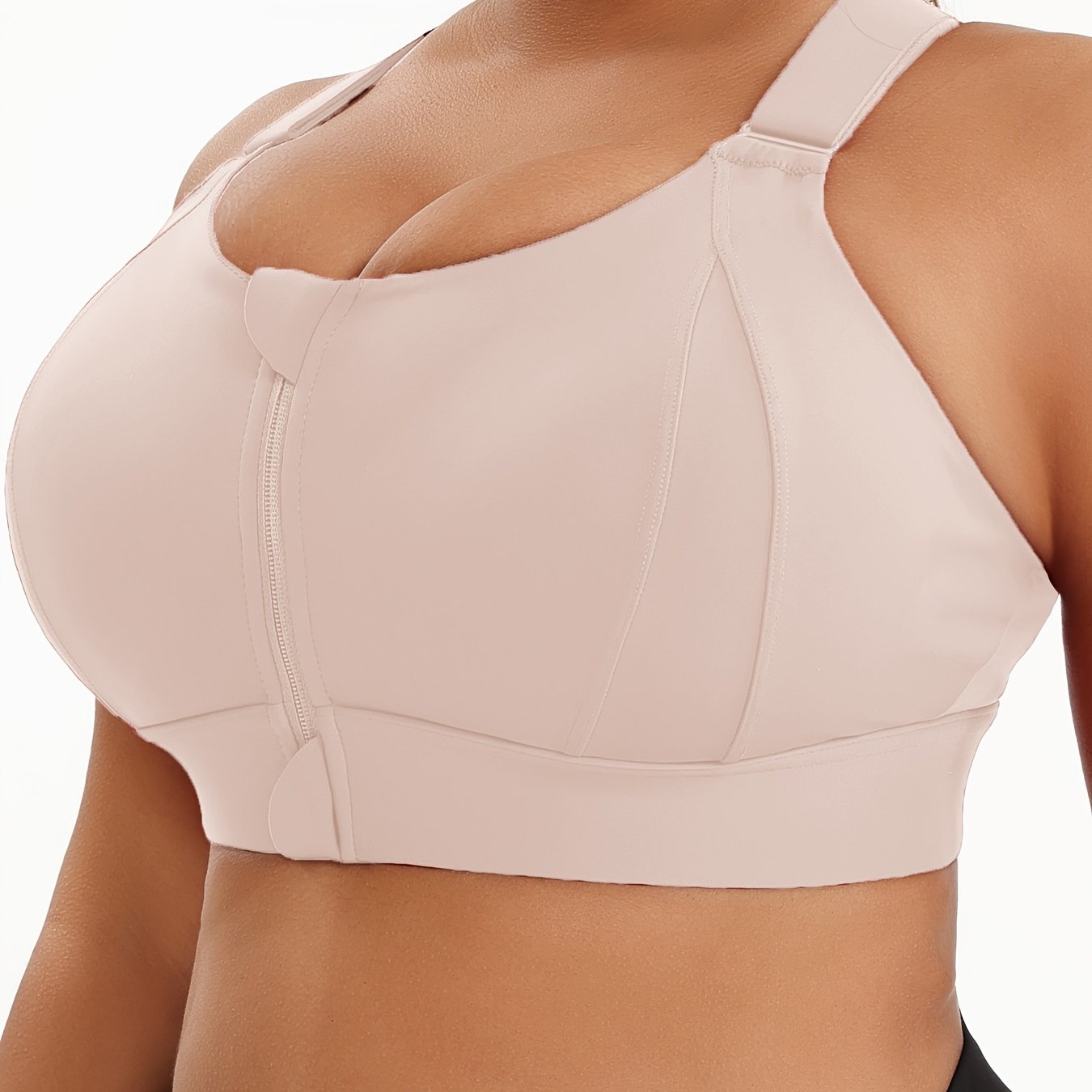 A woman wearing a beige plus size sports bras with criss-cross back design sold by 100 Spartans