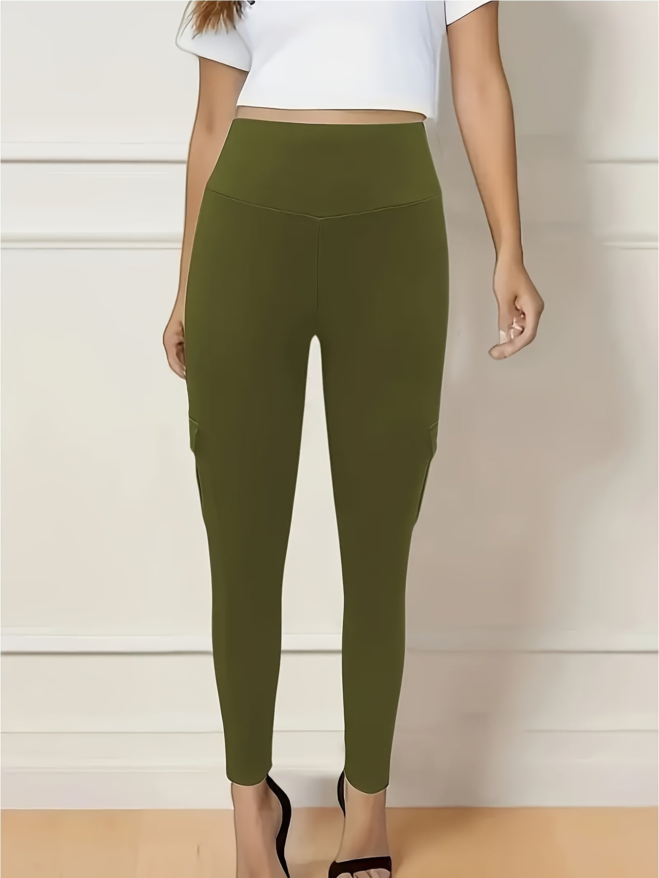 Person wearing olive green yoga leggings with a white top against a neutral background