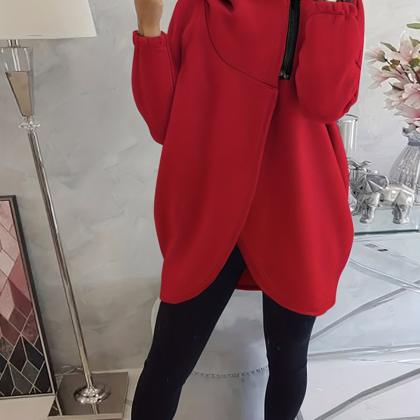 A person wearing a red women’s oversized zip-up hoodie