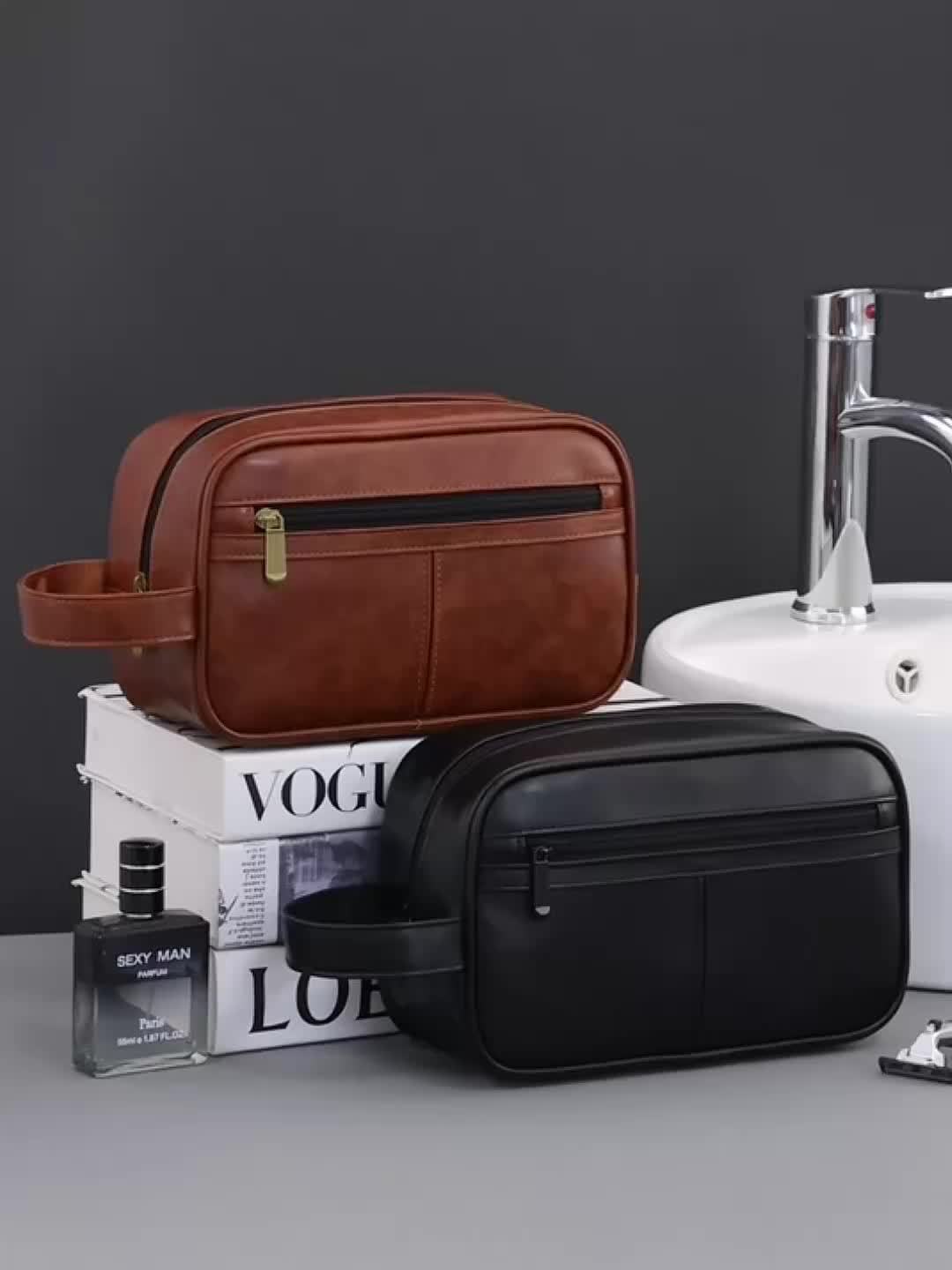 Brown and black leather toiletry bags on a magazine with a sink in the background