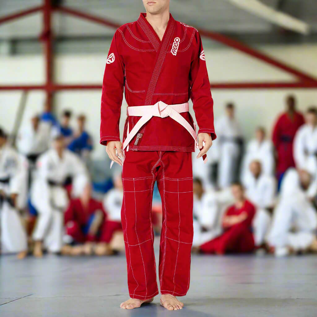 Person wearing a red martial arts uniform with white belts in a dojo setting.