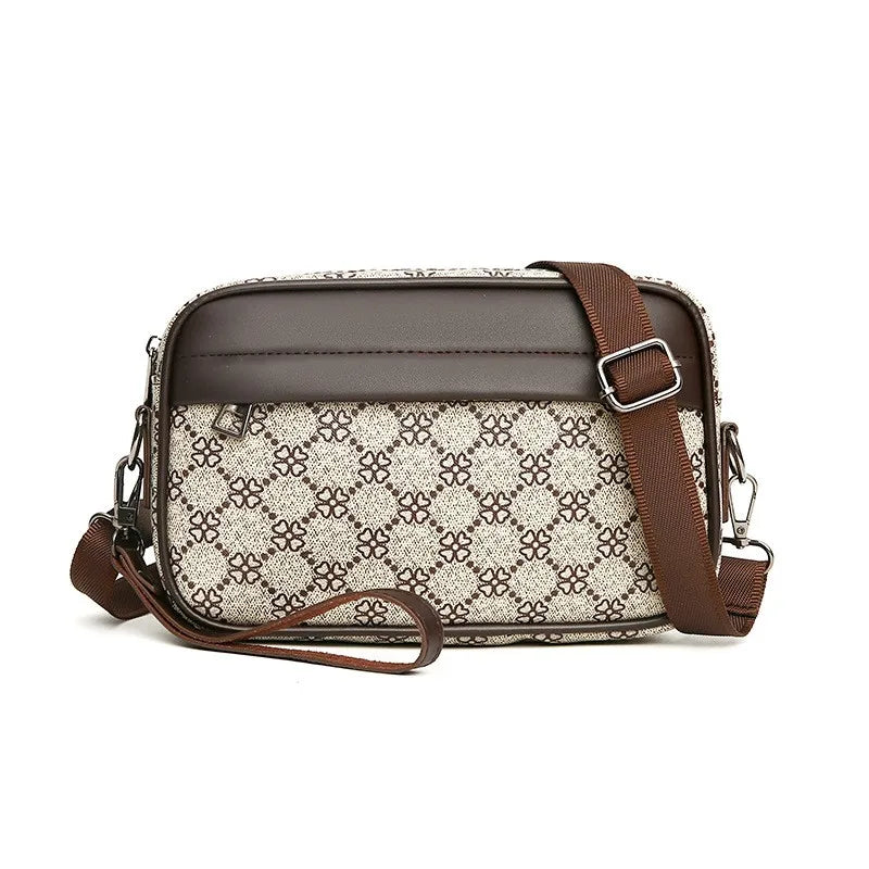 Leather toiletry bag with patterned front and brown strap on a white background