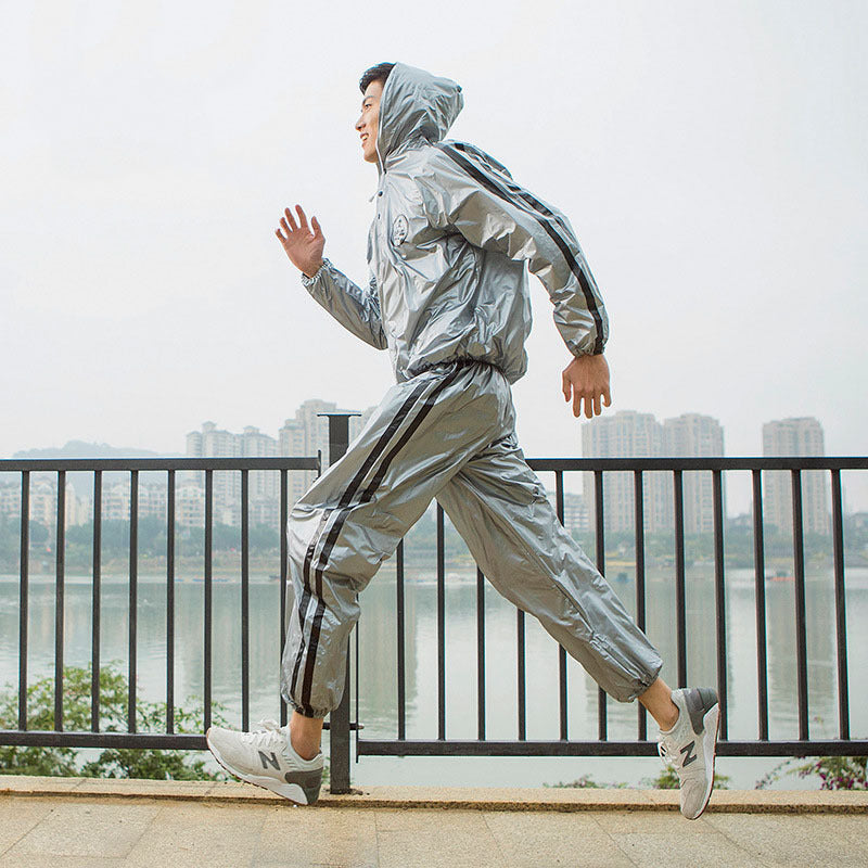 Person running outdoors wearing a reflective silver tracksuit with a cityscape in the background.