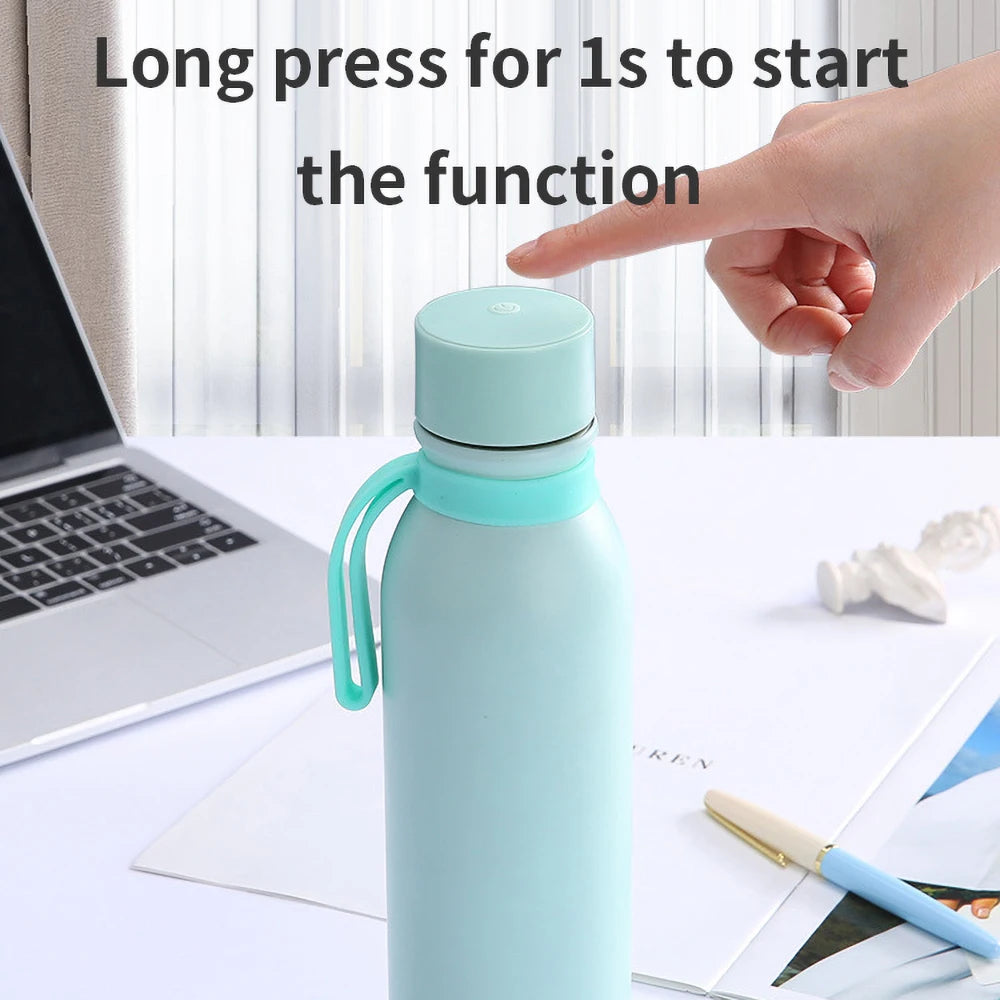 A light green smart water bottles sold by 100 Spartans placed on a work table beside a laptop, its being turned on