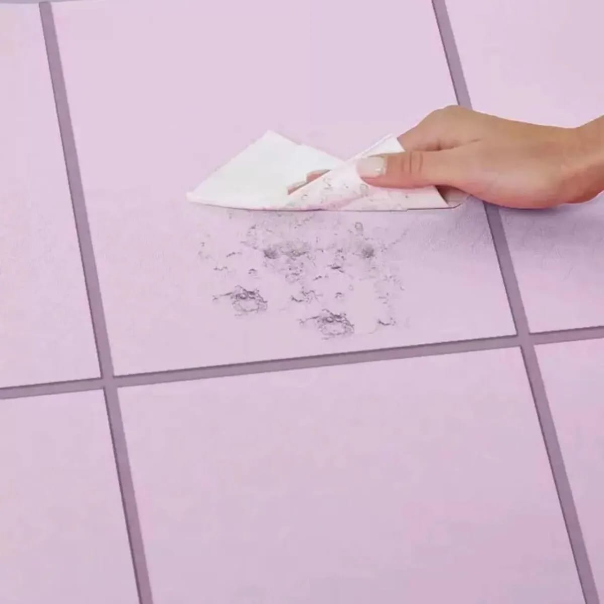 Cleaning a purple foldable yoga mat sold by 100 Spartans with paper towel.