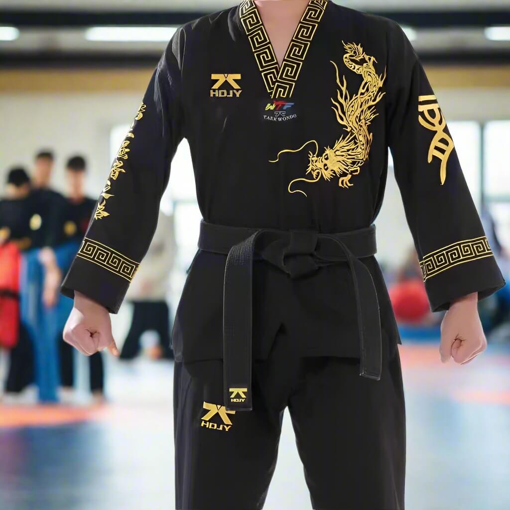 Person wearing a black taekwondo uniform with gold embroidery in an indoor setting