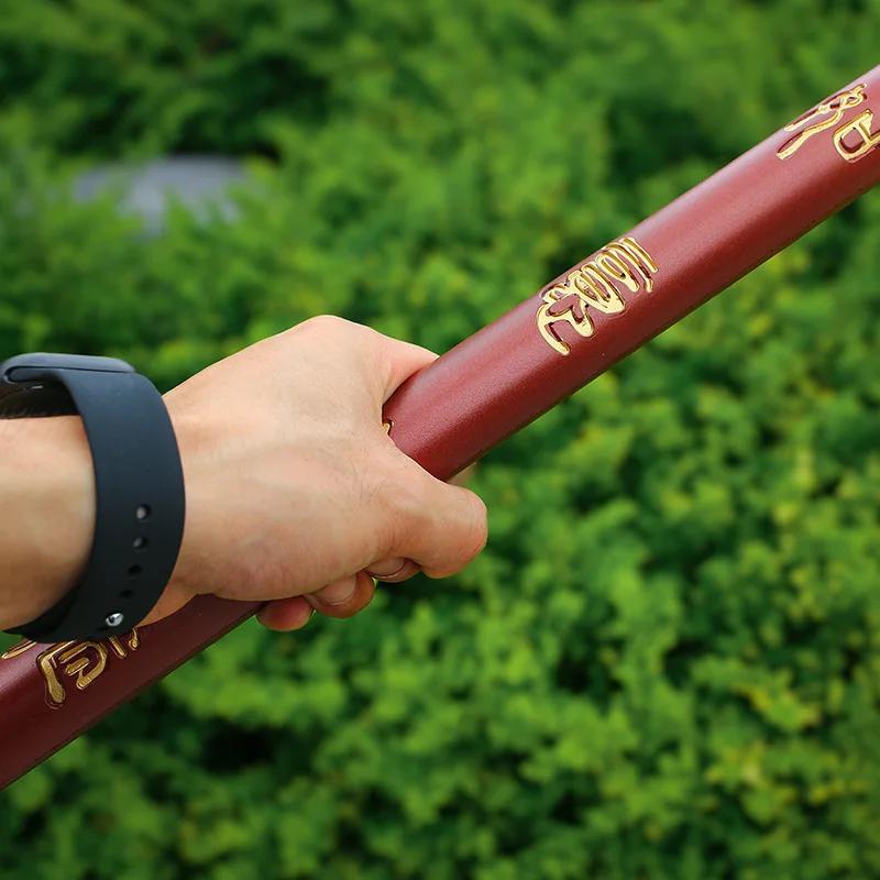 Hand holding a Sun Wukong Stick with gold text against a green blurred background