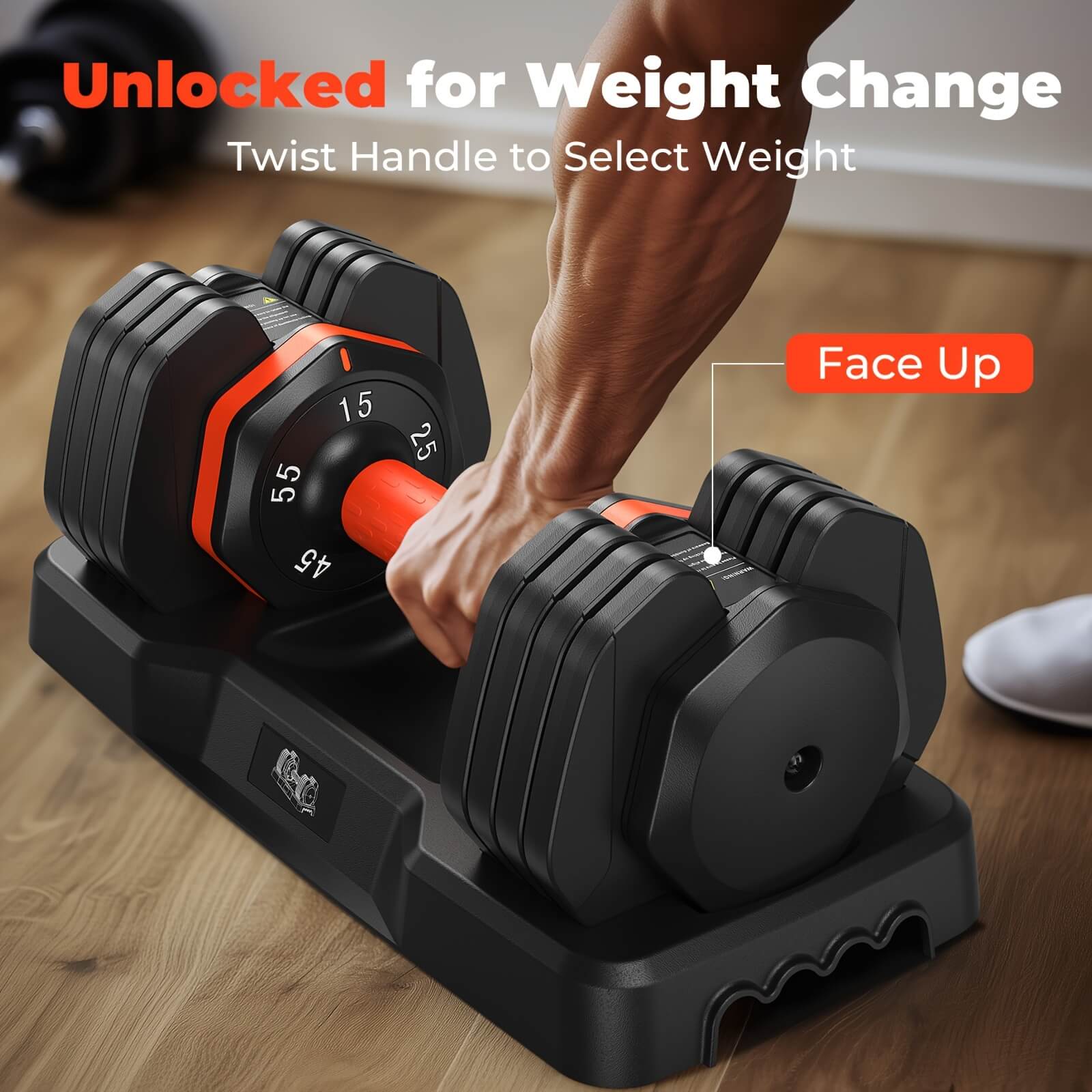 Pair of adjustable dumbbells with a hand selecting weight on a wooden floor.