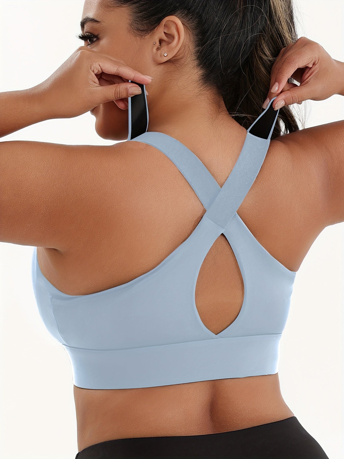 A woman wearing a light blue plus size sports bras with criss-cross back design sold by 100 Spartans
