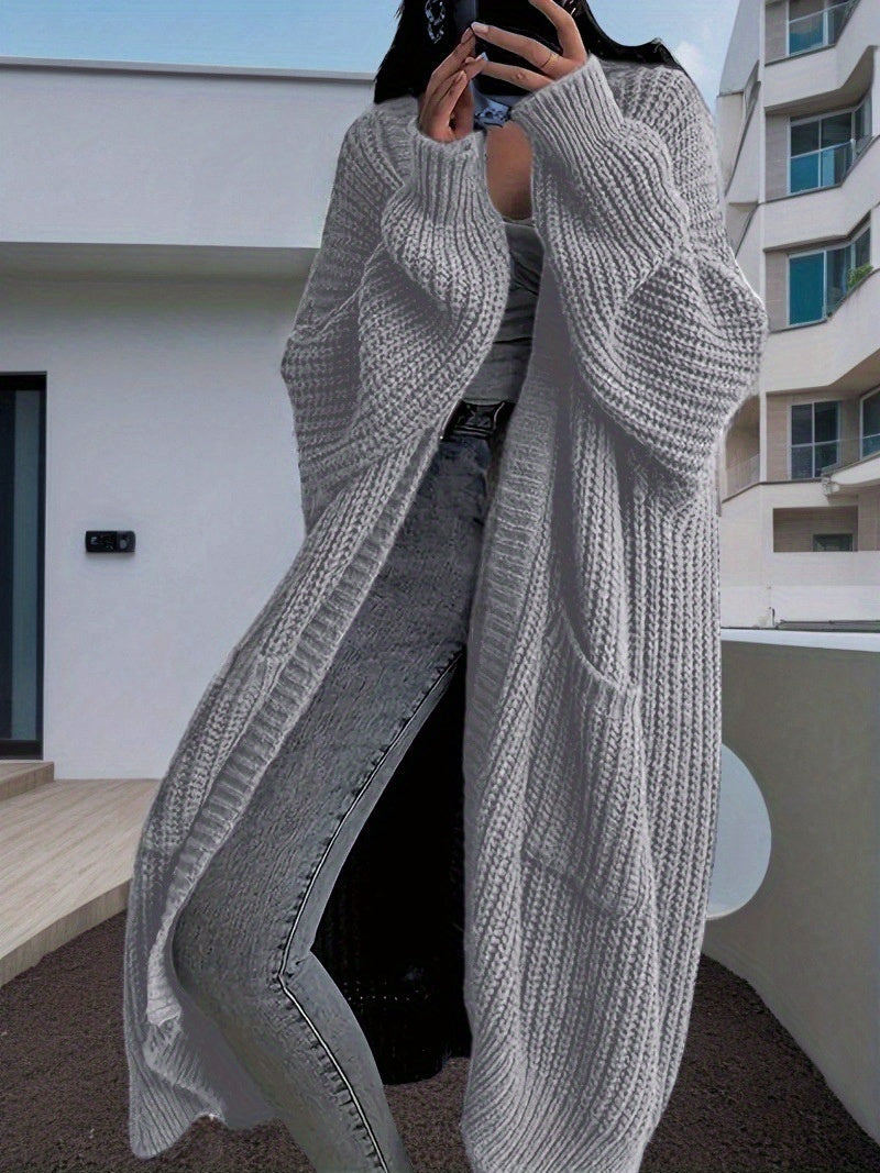 Person wearing a long gray knit cardigan in an urban setting