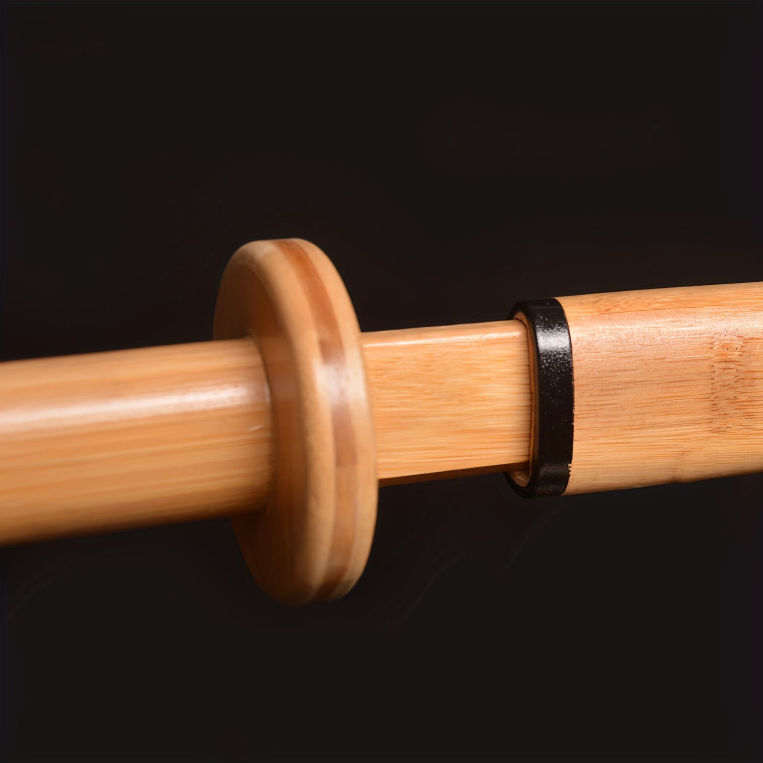 Close-up of a wooden training sword with a black band on a dark background