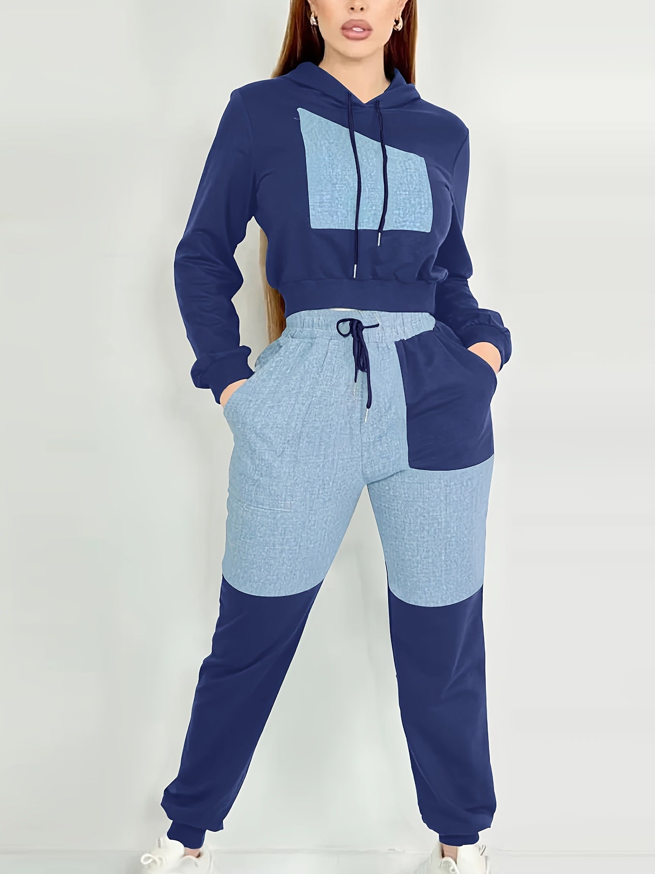 Person wearing a blue and navy color-blocked women's luxury tracksuit set on a white background