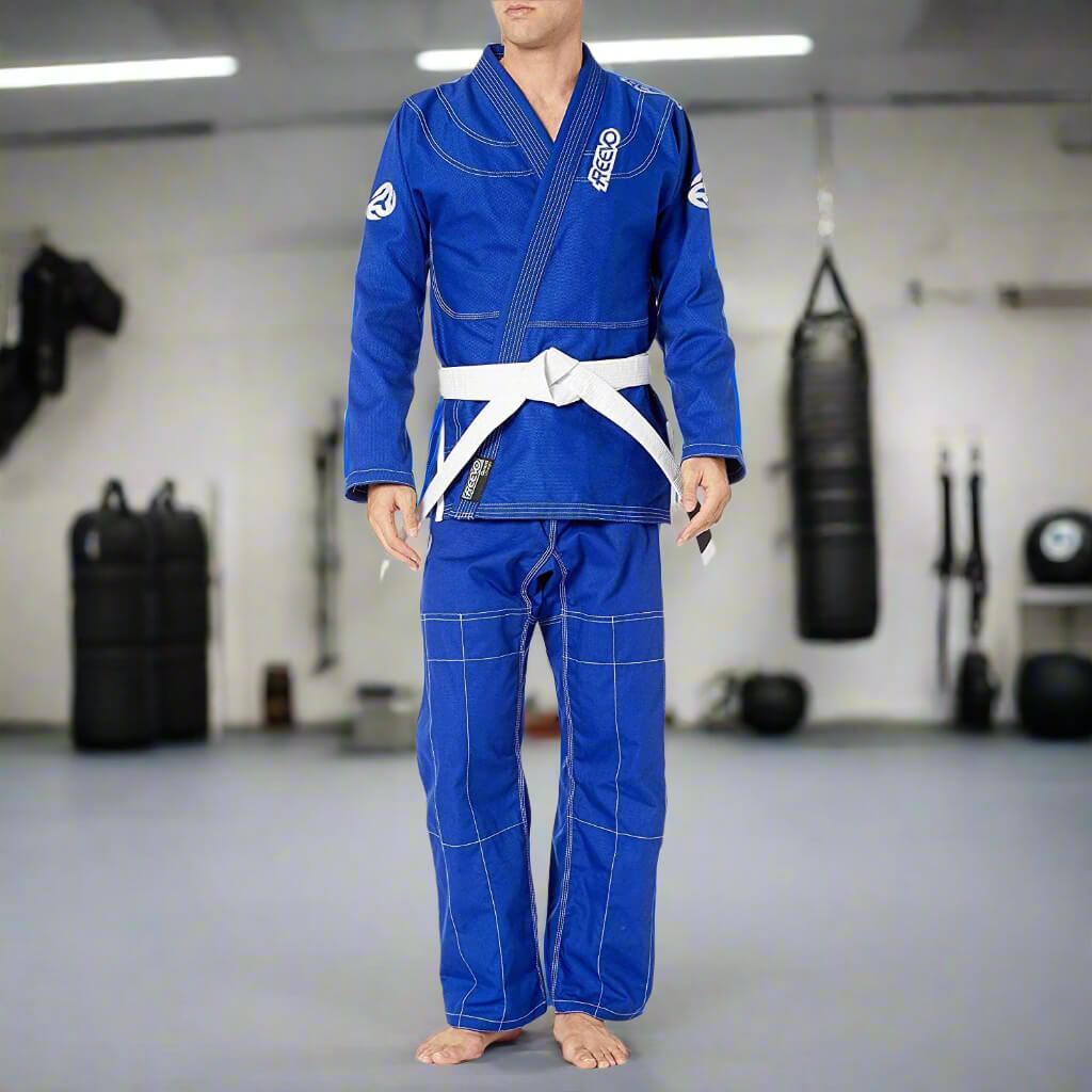 Person wearing a blue martial arts uniform with white belt in a gym setting