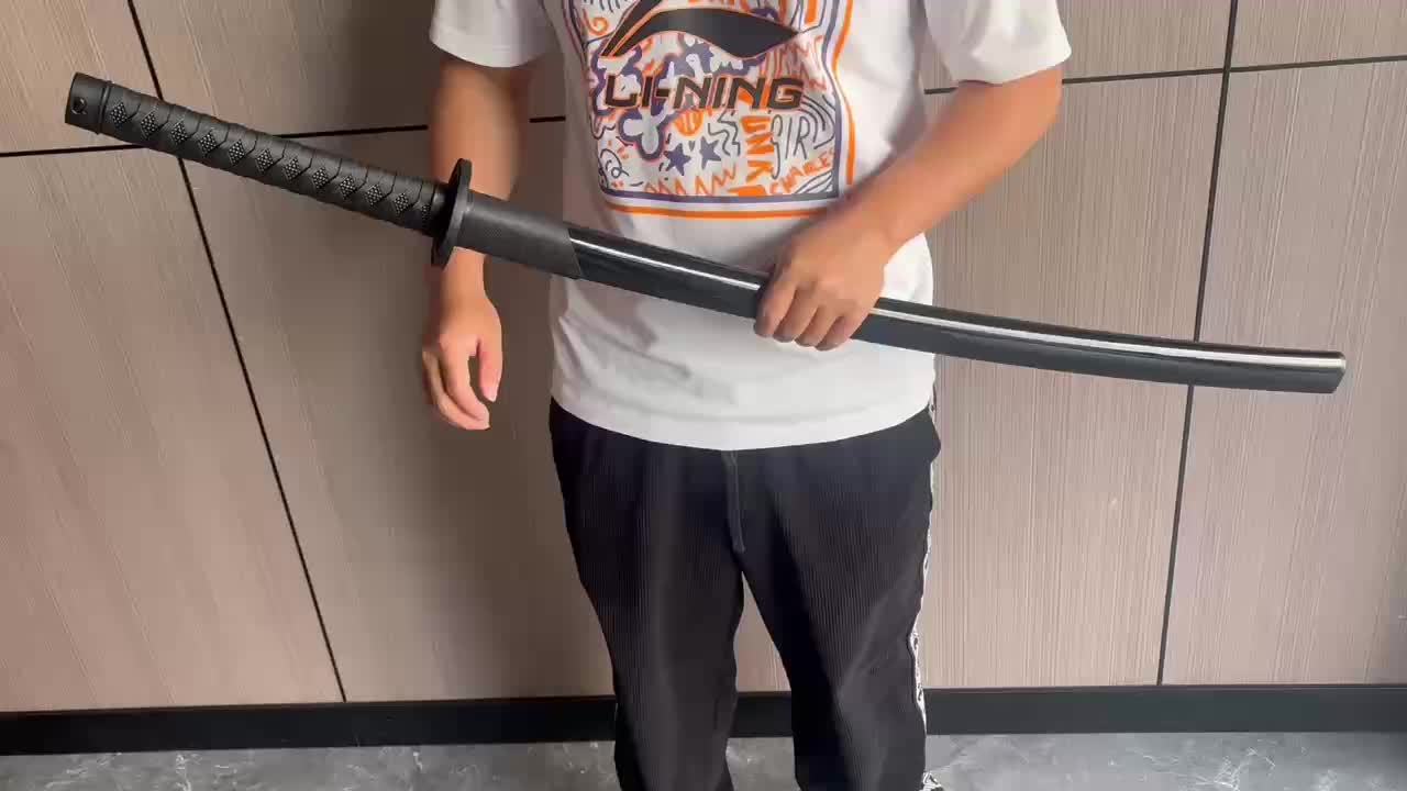 Person holding a black training sword against a tiled wall background