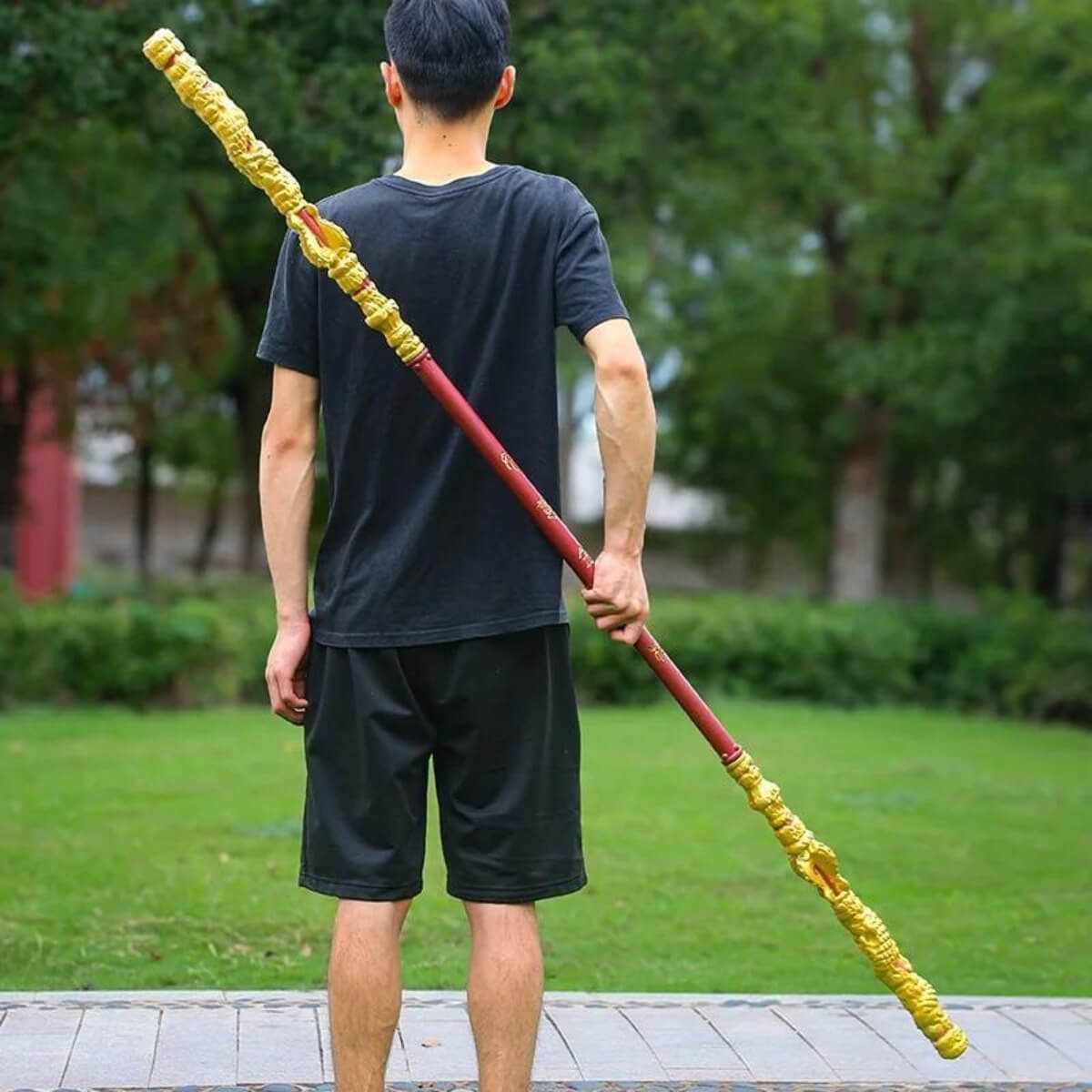 Person holding a large yellow and red Sun Wukong Stick in an outdoor setting