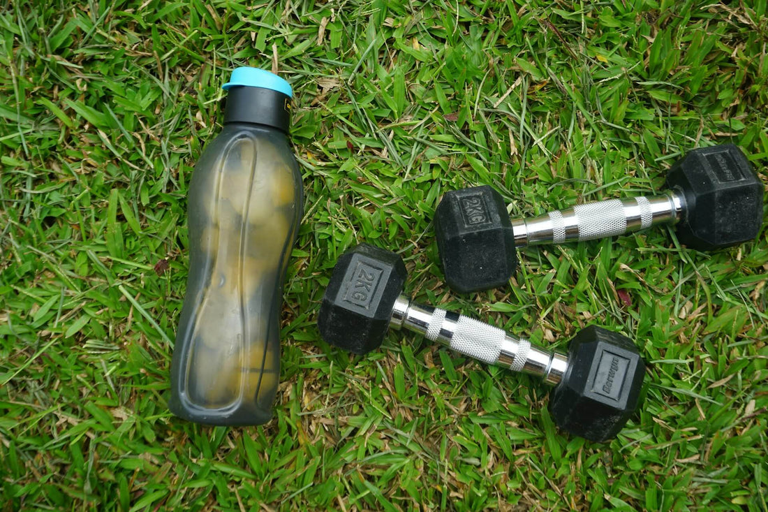 A sports water bottle beside 2 dumbbells