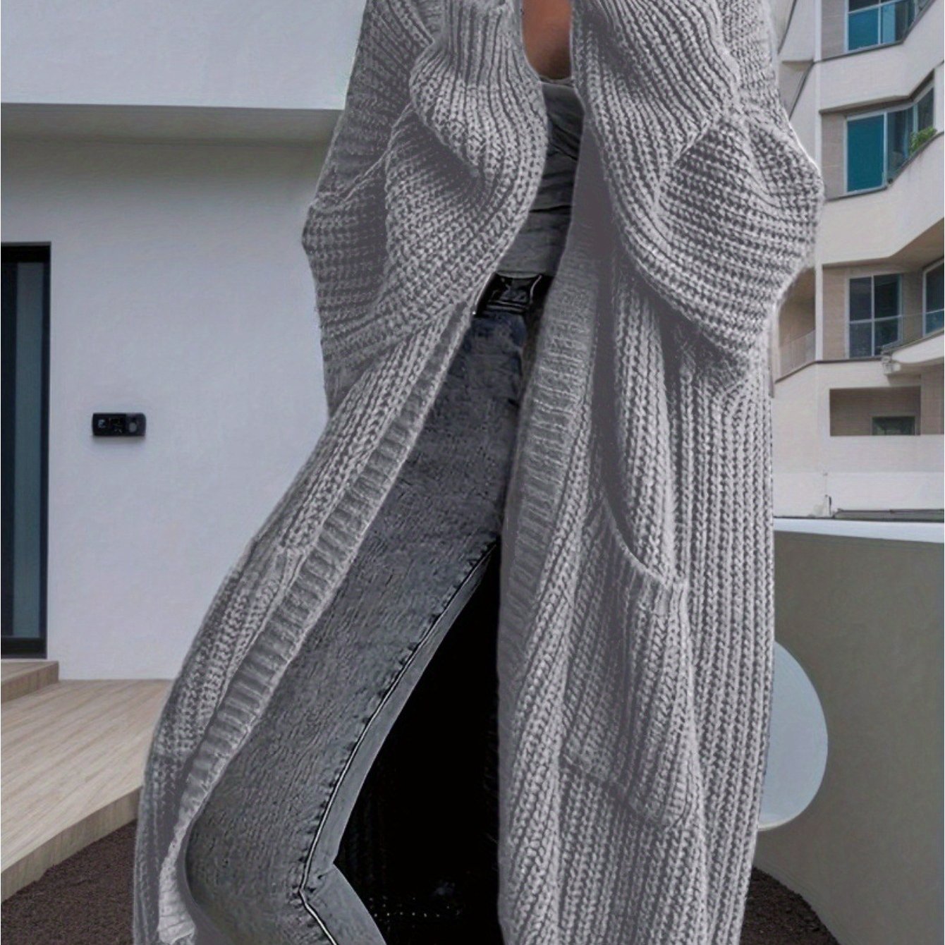 Person wearing a gray knitted cardigan with a blurred background