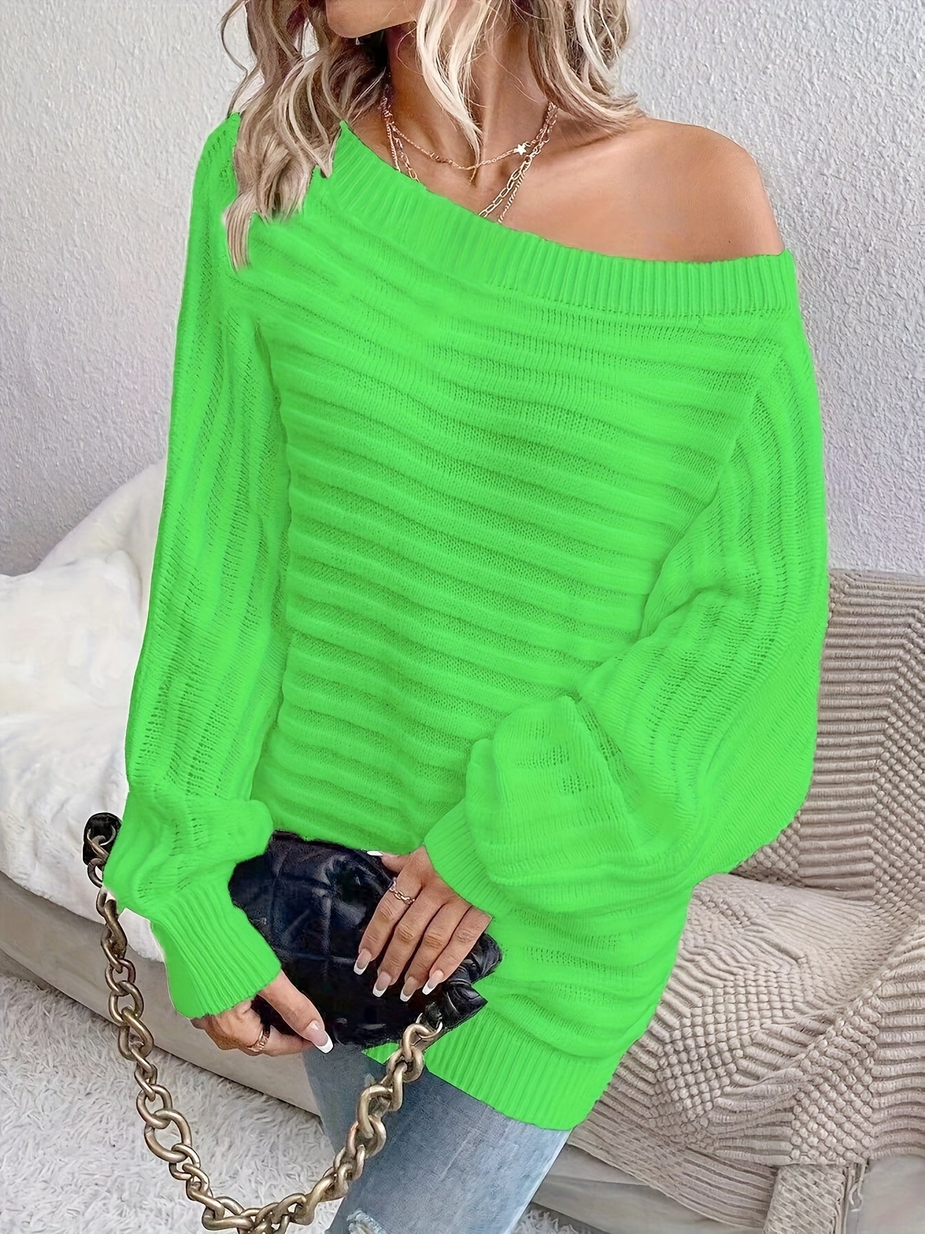 Person wearing a bright green off shoulder sweater holding a black clutch.