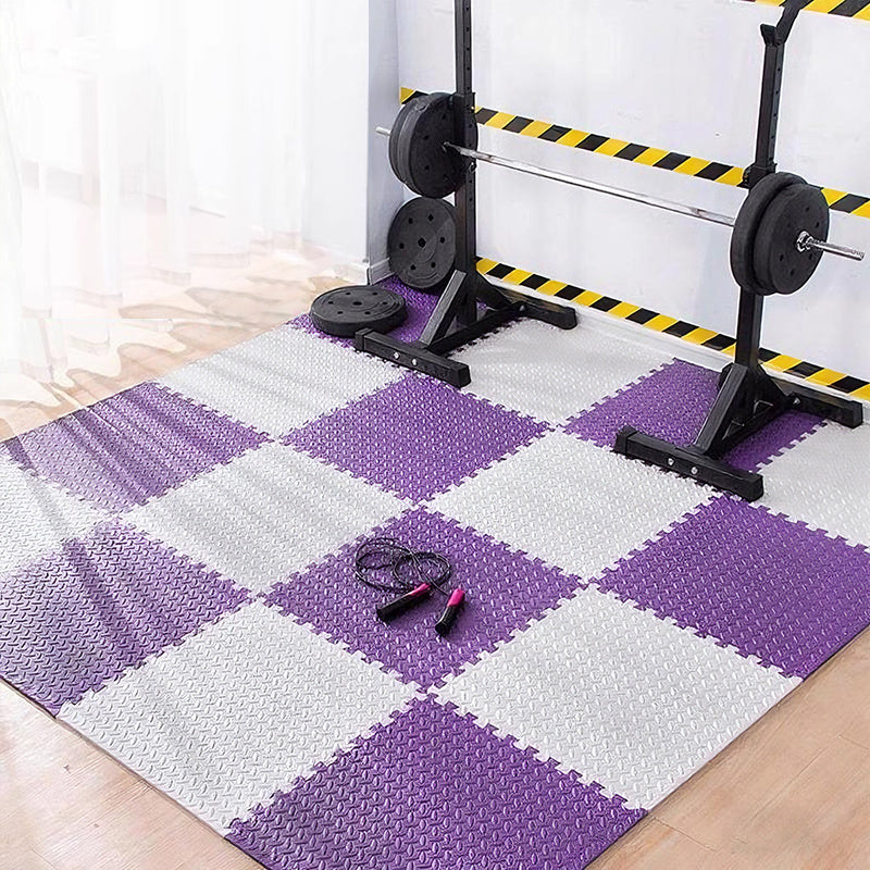 Purple and white checkered foam puzzle mat with weightlifting equipment in the background.