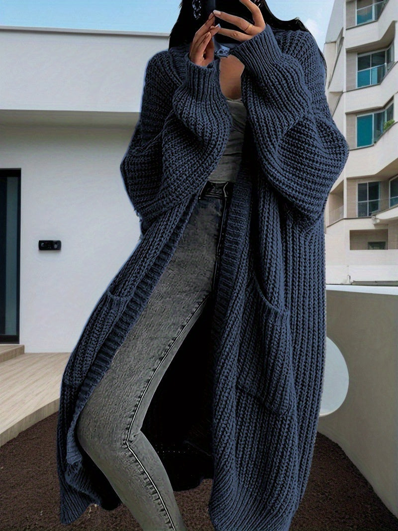Person wearing a long dark blue knitted cardigan in an urban setting