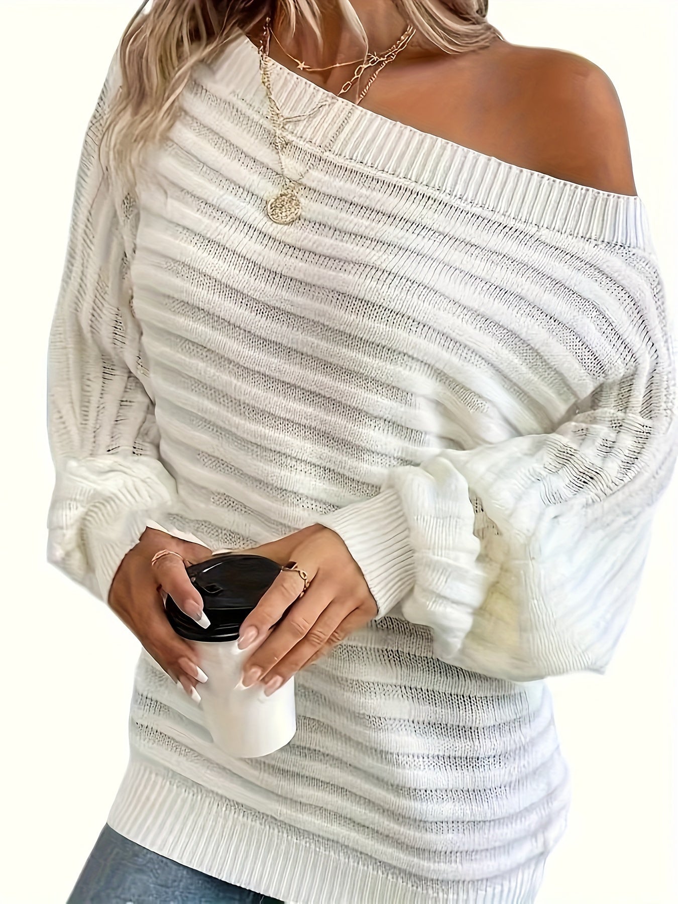 Woman wearing a white off shoulder sweater holding a coffee cup.
