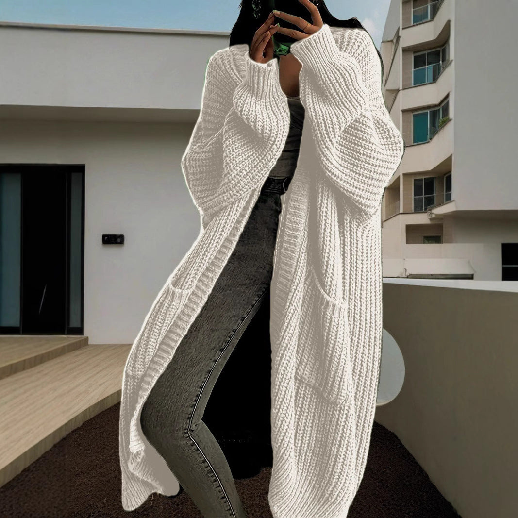 Person wearing a long white knitted cardigan in an urban setting