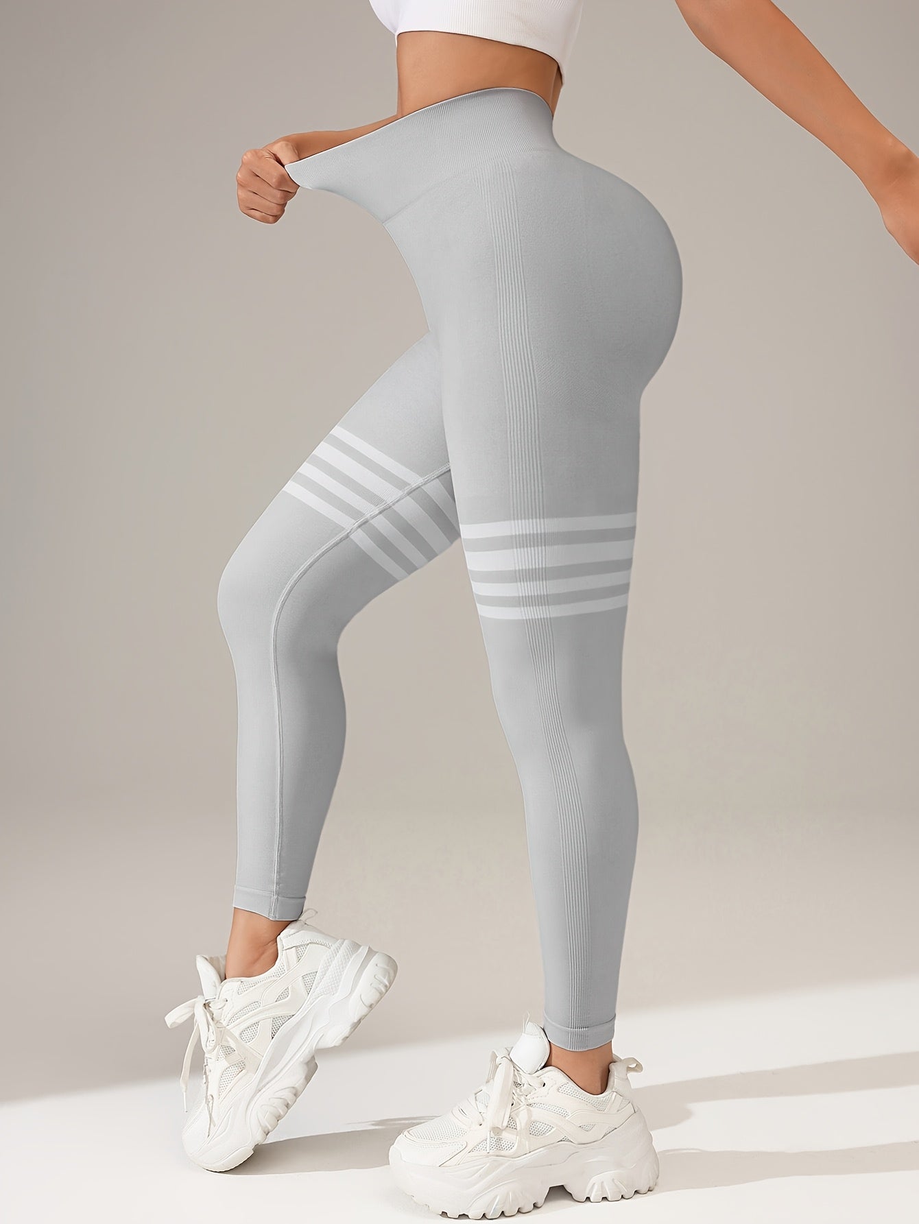 A woman wearing a pale grey yoga legging sold by 100 Spartans