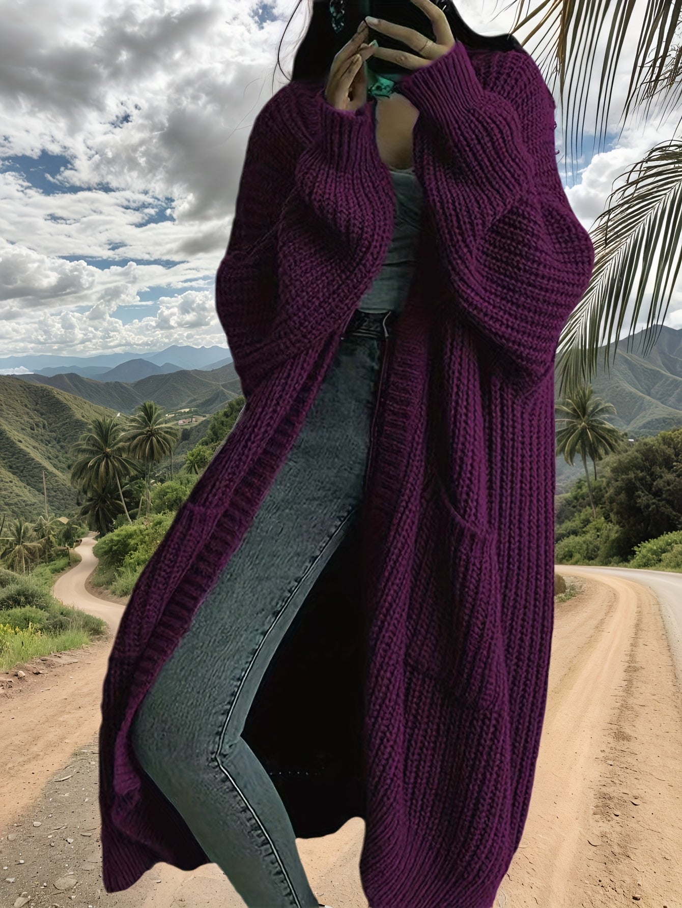 Person wearing a long purple cardigan in a scenic outdoor setting with mountains and palm trees.