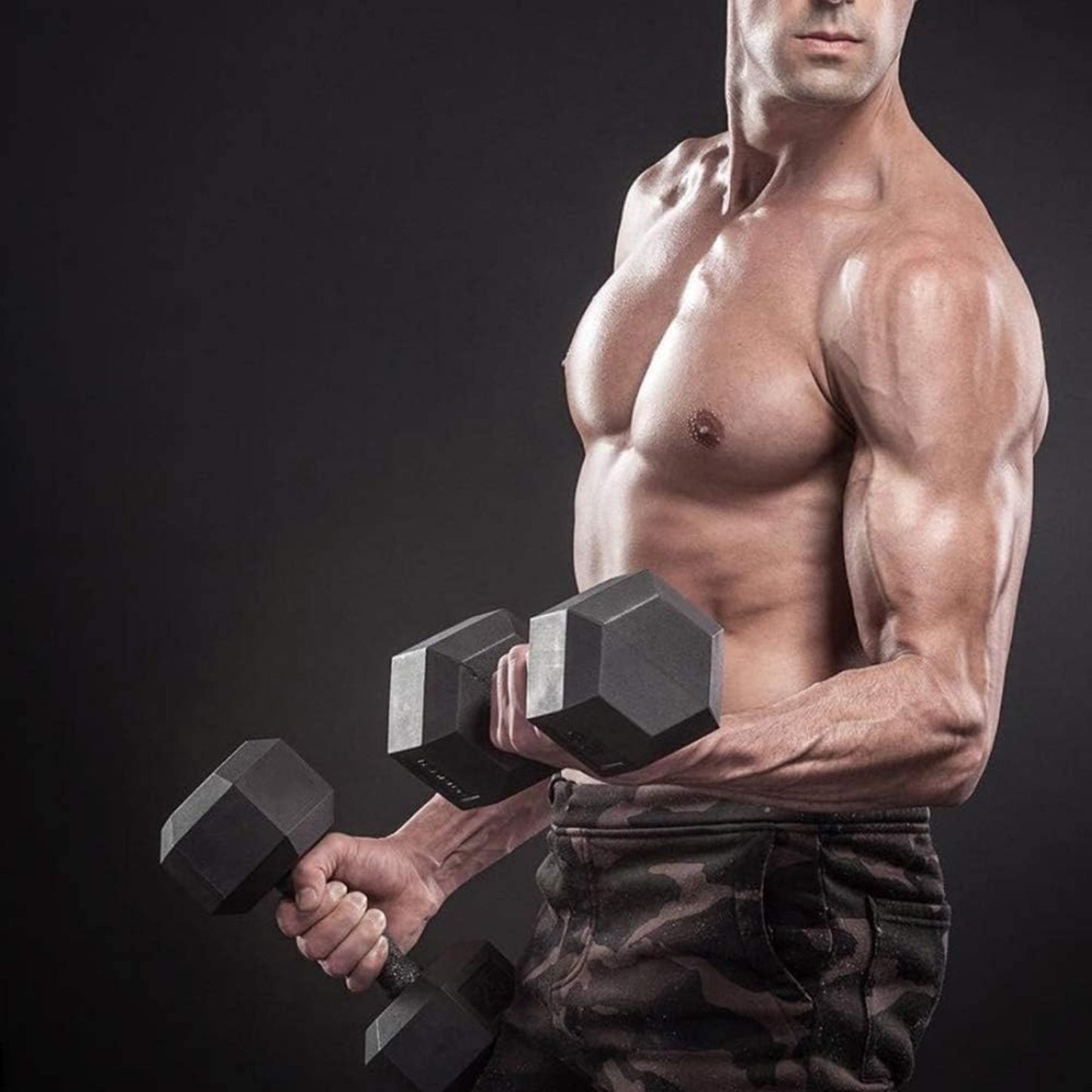 Muscular man holding two dumbbells against a dark background