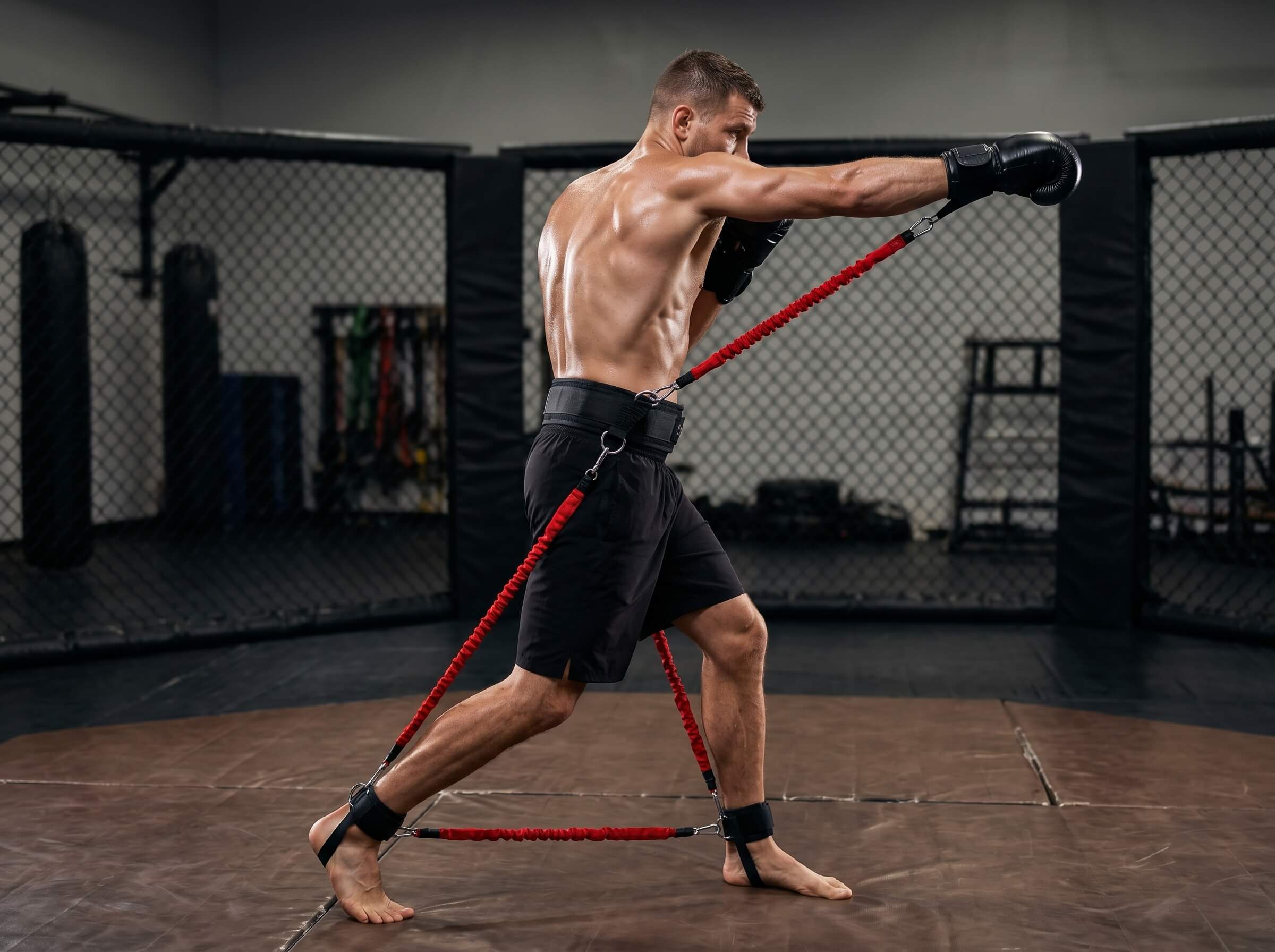 Man training with a red resistance bands set in a boxing ring