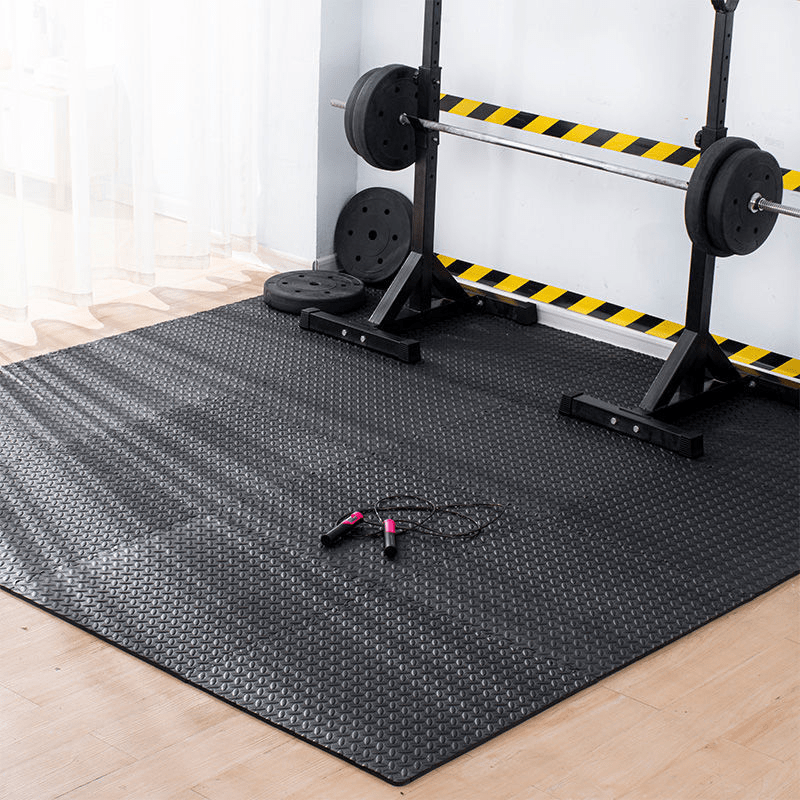 Gym mat with weightlifting equipment on a wooden floor