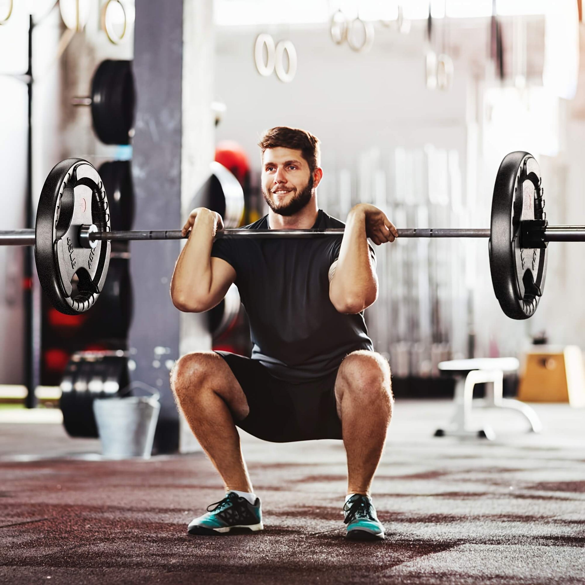 Man performing a barbell squat in a gym setting