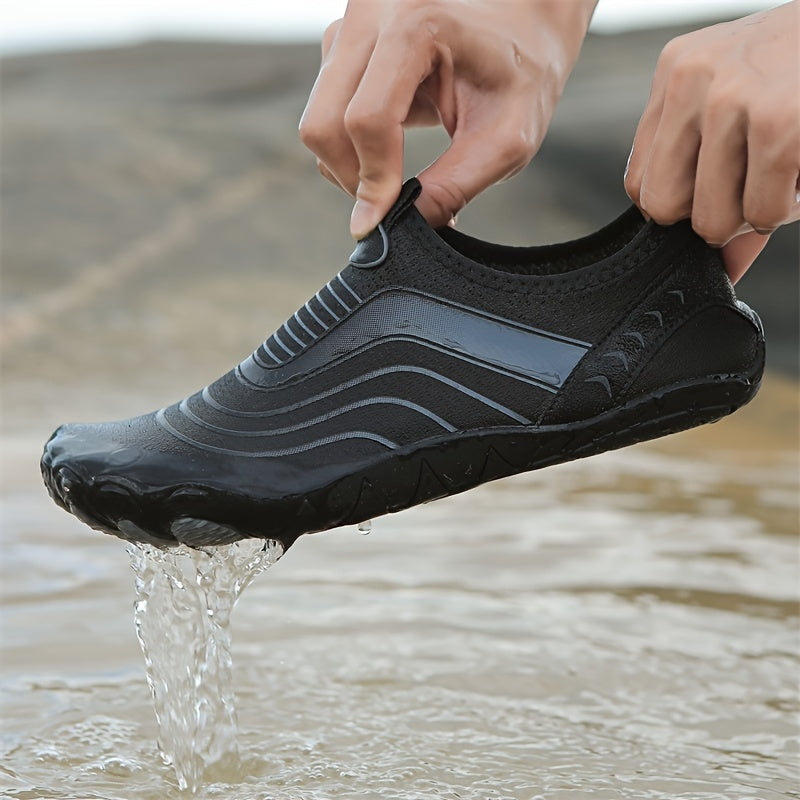 Person wearing a black water hiking shoes with wavy patterns, standing in water.
