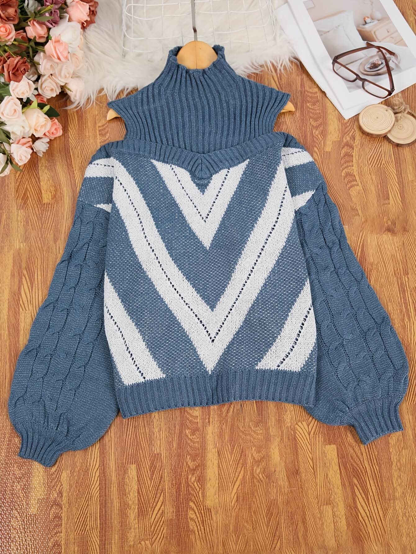 Blue off the shoulder sweater with white geometric pattern on a wooden surface