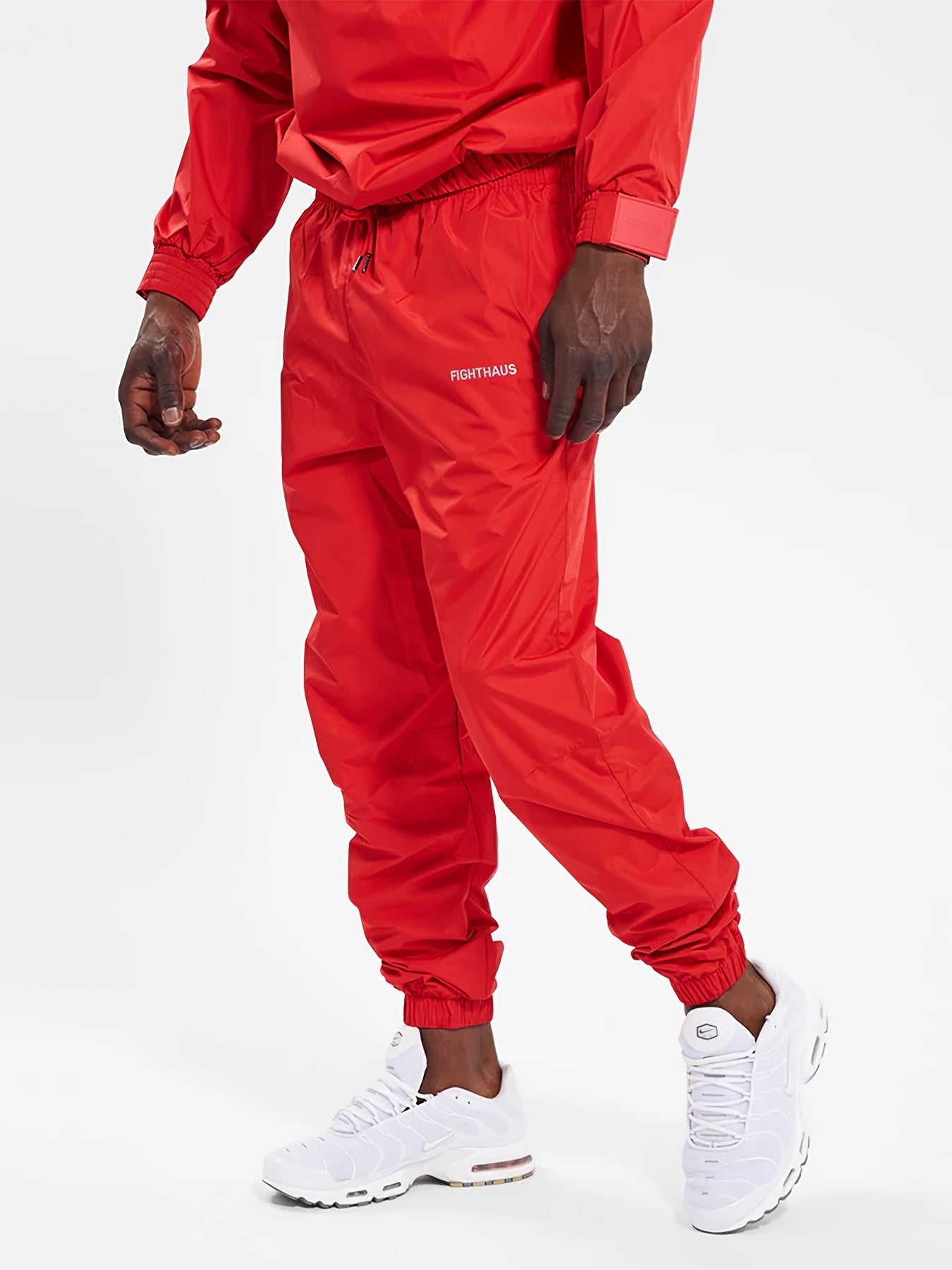 Person wearing a red mens sauna sweat suit with white sneakers on a white background