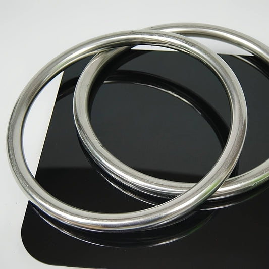 Two wing chun rings on a reflective black surface with a white background