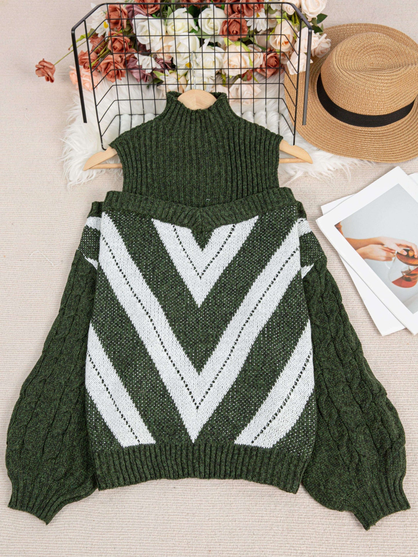 Green off the shoulder sweater with white chevron pattern on a light surface with decorative items.